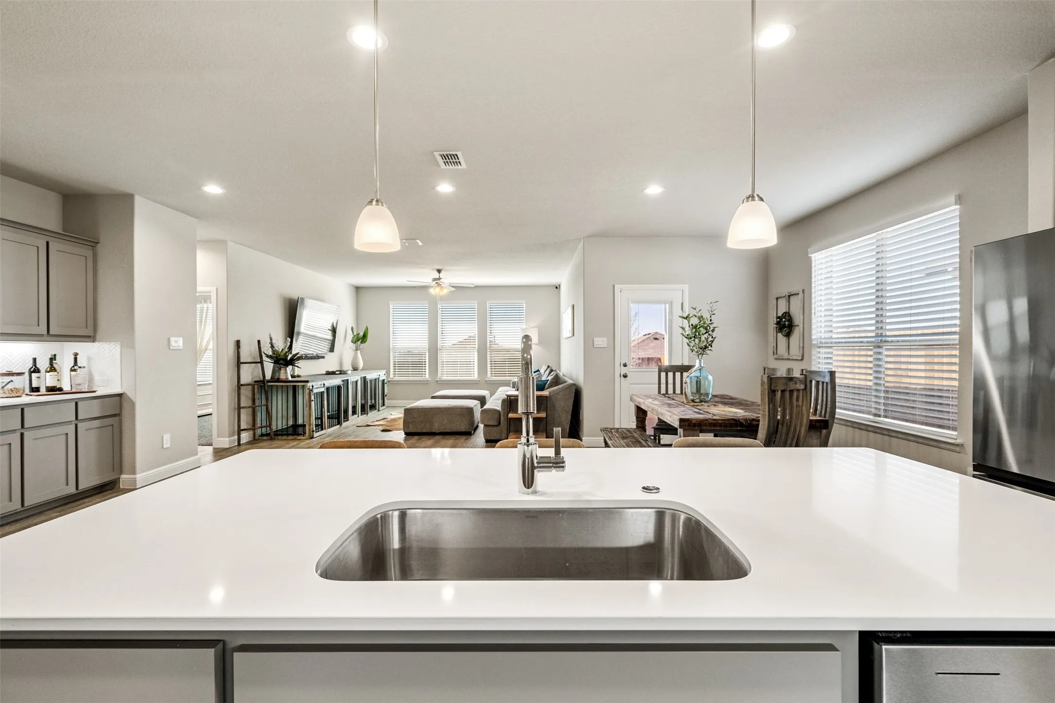 Kitchen with gray cabinets, open floor plan, freestanding refrigerator, and decorative light fixtures