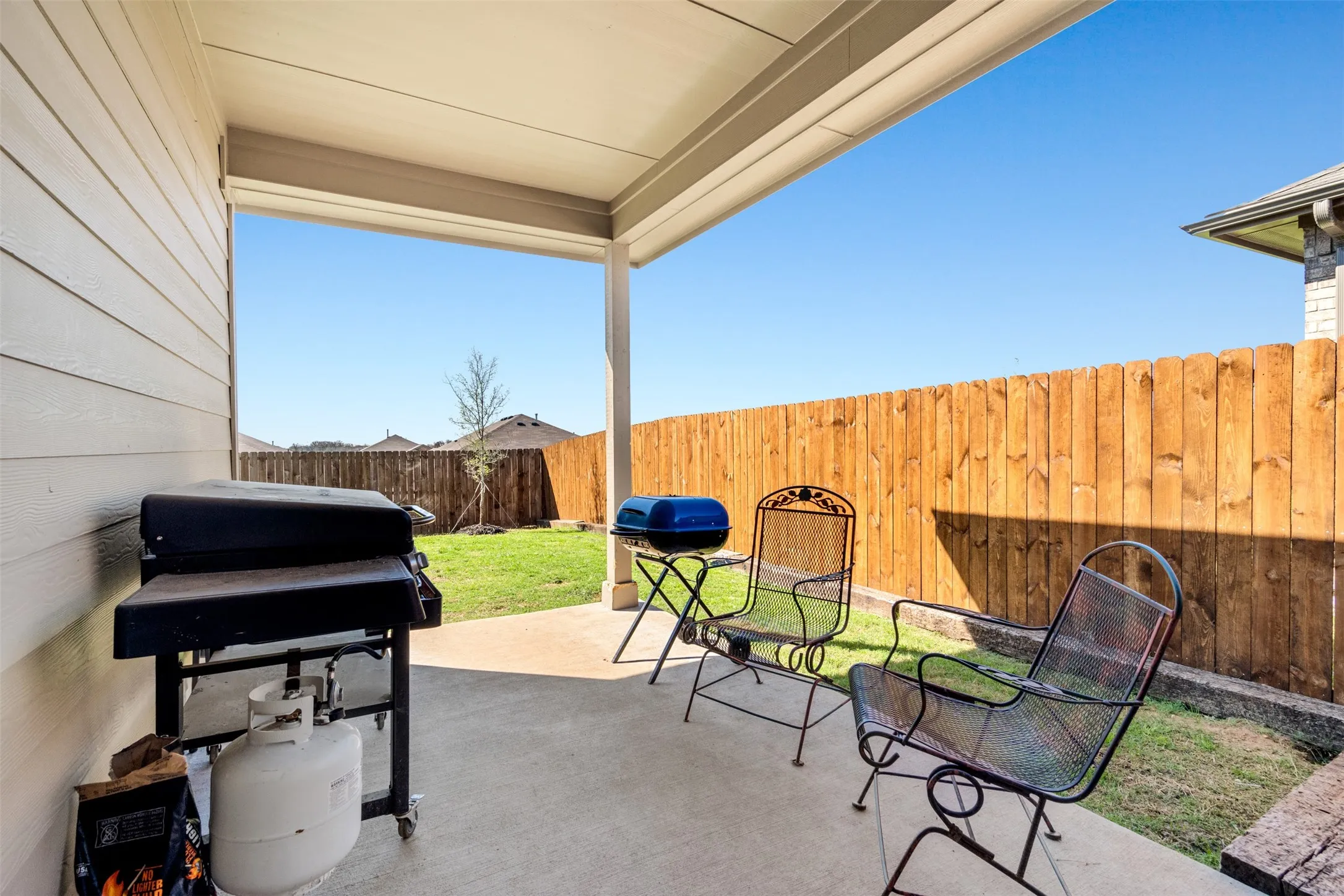 Fenced backyard featuring a patio area and grilling area