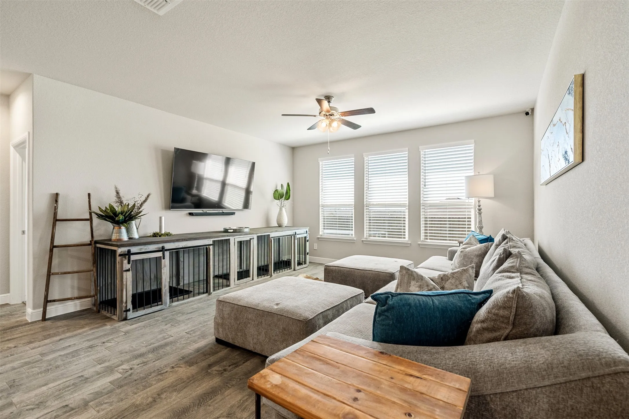 Living area with a ceiling fan, wood finished floors, and a textured ceiling
