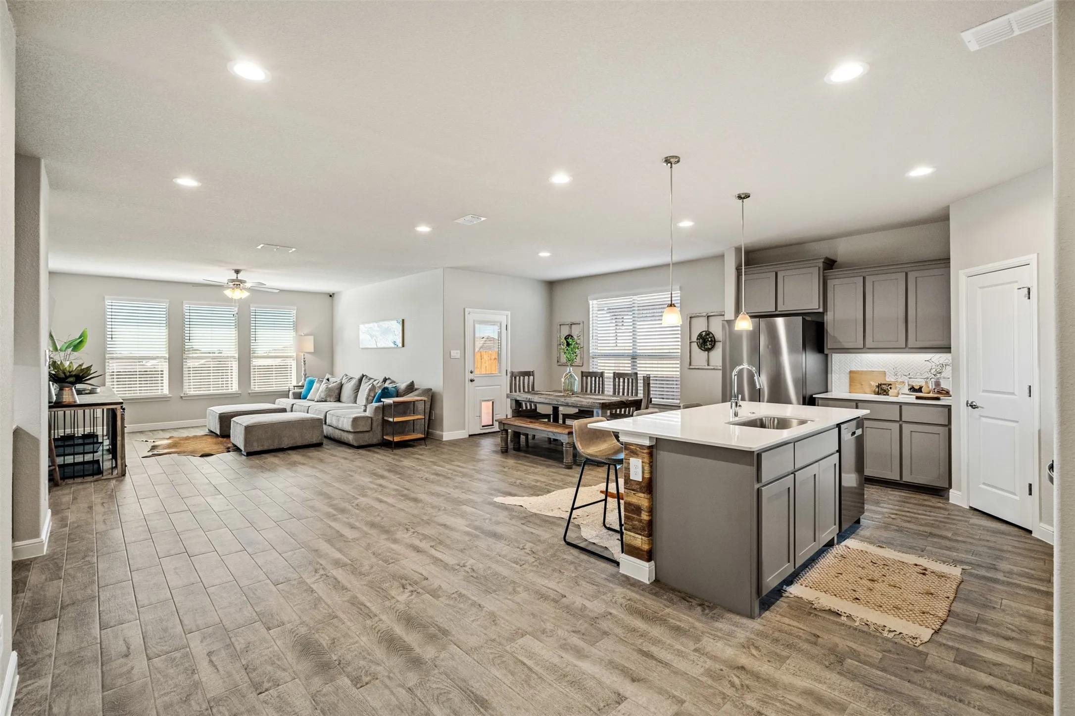 Kitchen with gray cabinetry, open floor plan, a breakfast bar area, a center island with sink, and healthy amount of natural light