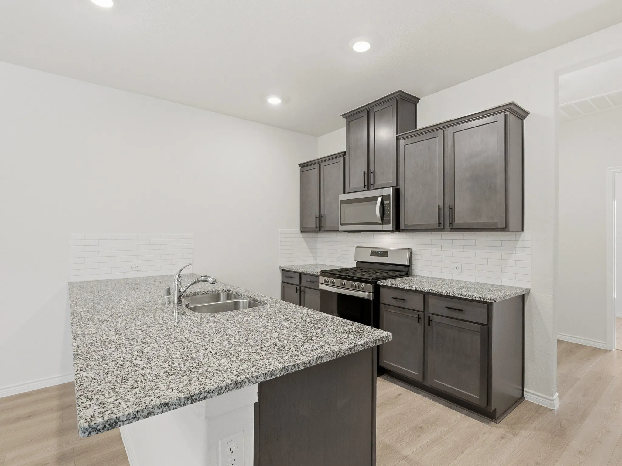 Modern kitchen featuring granite countertops, stainless appliances and newly added cabinet hardware.
