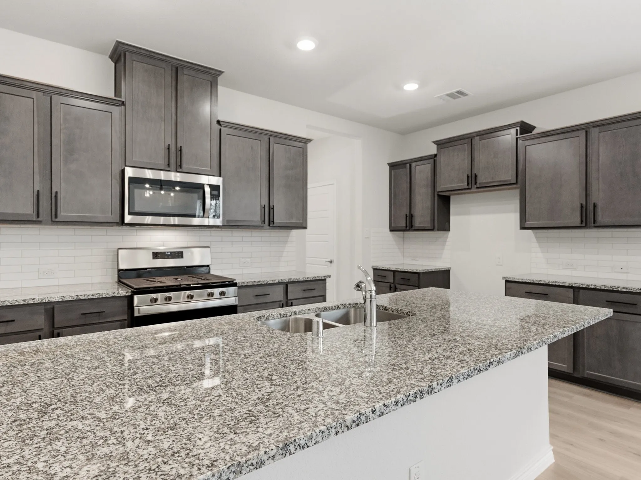 Modern kitchen featuring granite countertops, stainless steel appliances, and a large center island.