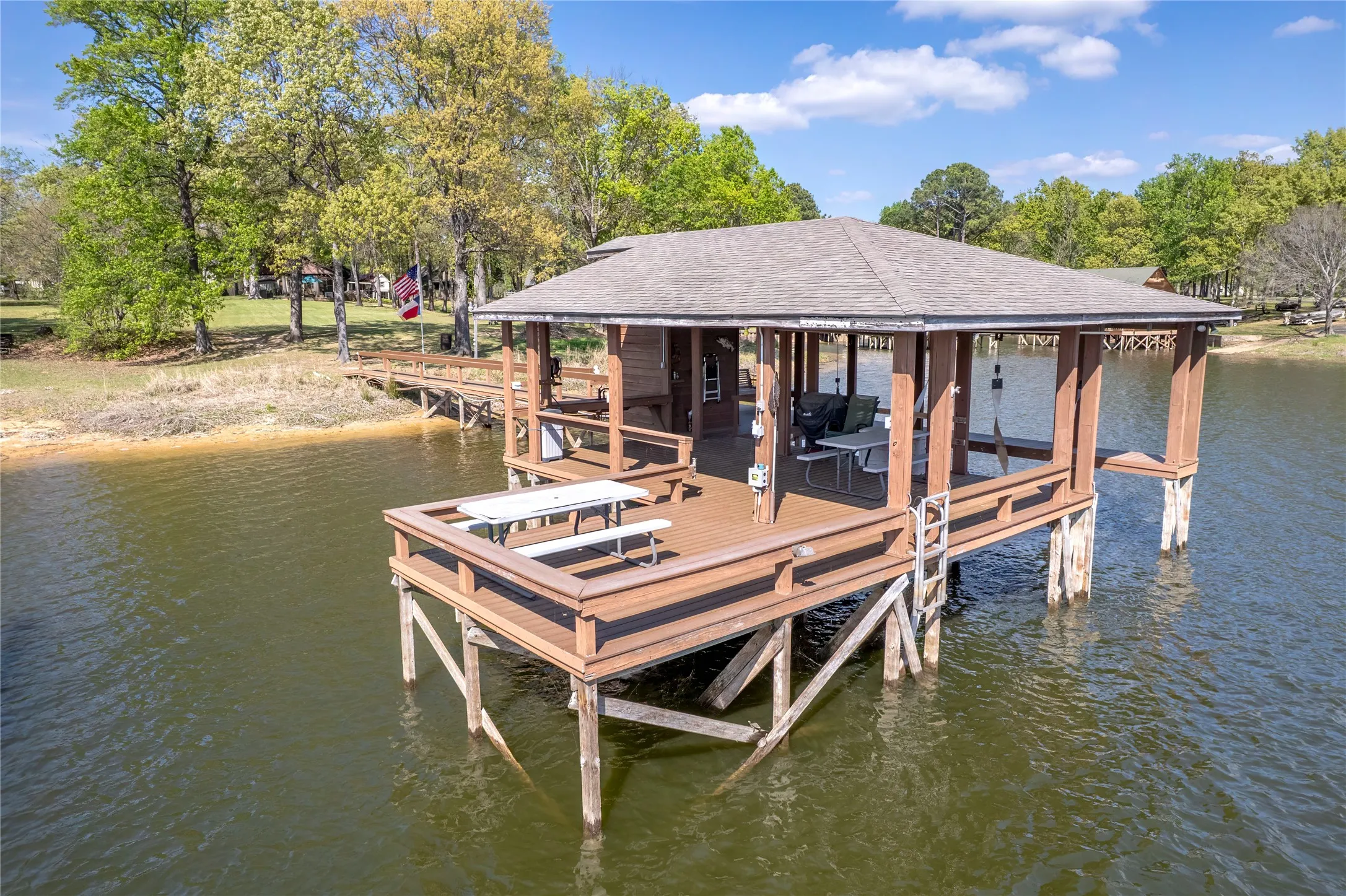 Dock featuring boat lift, a water view, and view of scattered trees