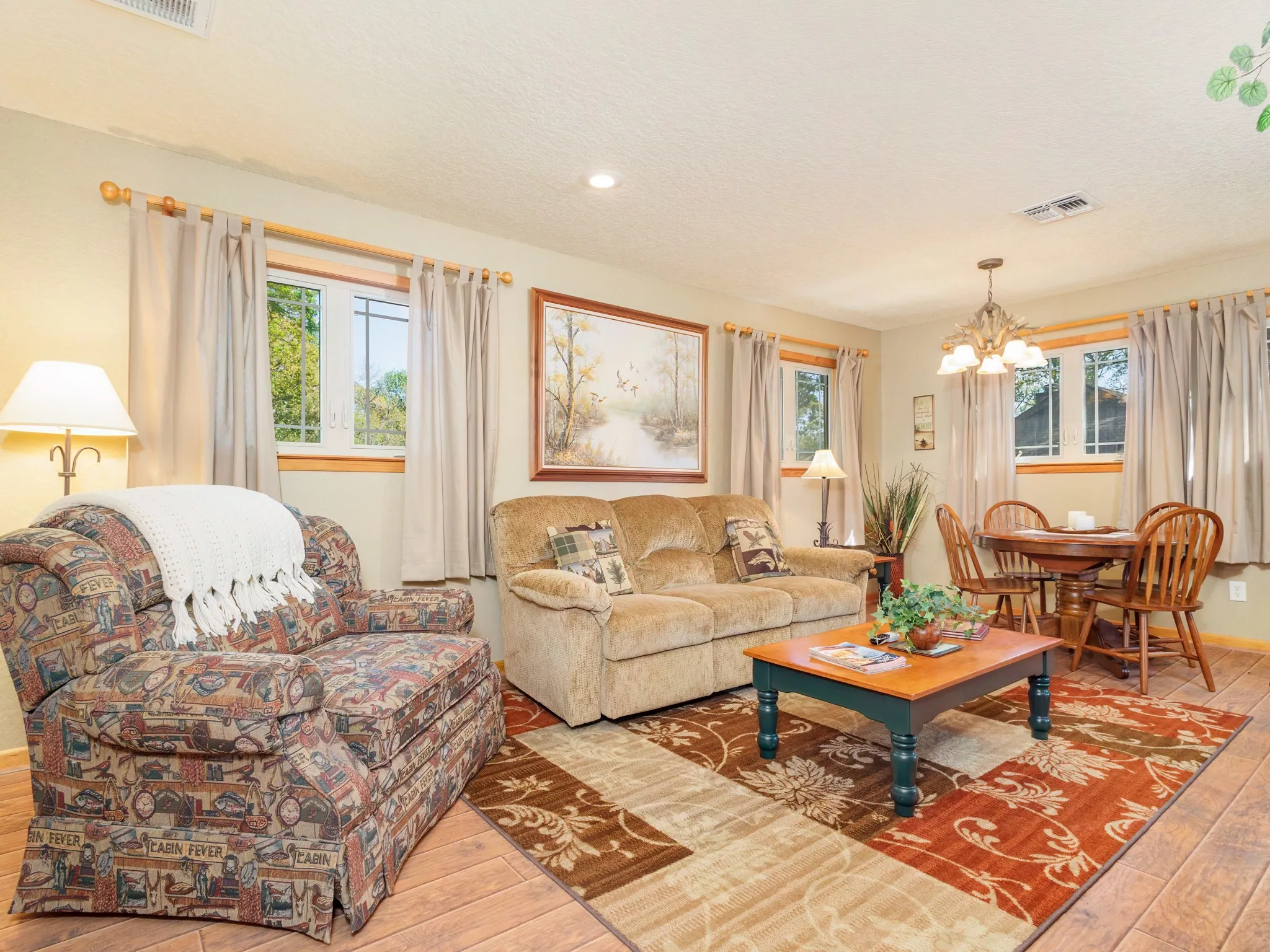 Guest Quarters Living room with light wood-style floors, a chandelier, and a textured ceiling