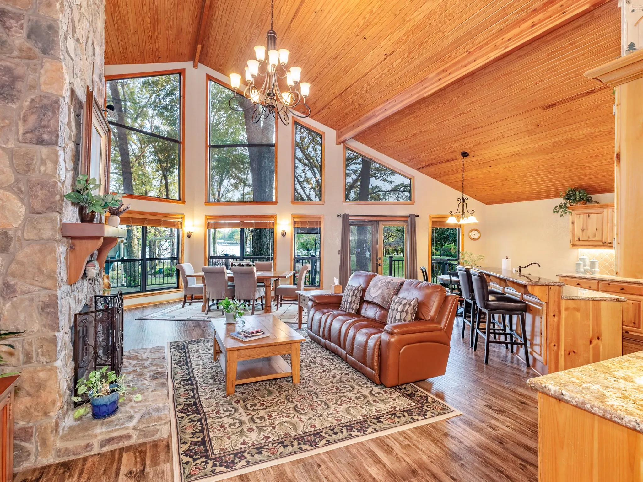 Living area with hanging lights, a fireplace, light wood-type flooring, a high wood ceiling, and healthy amount of natural light