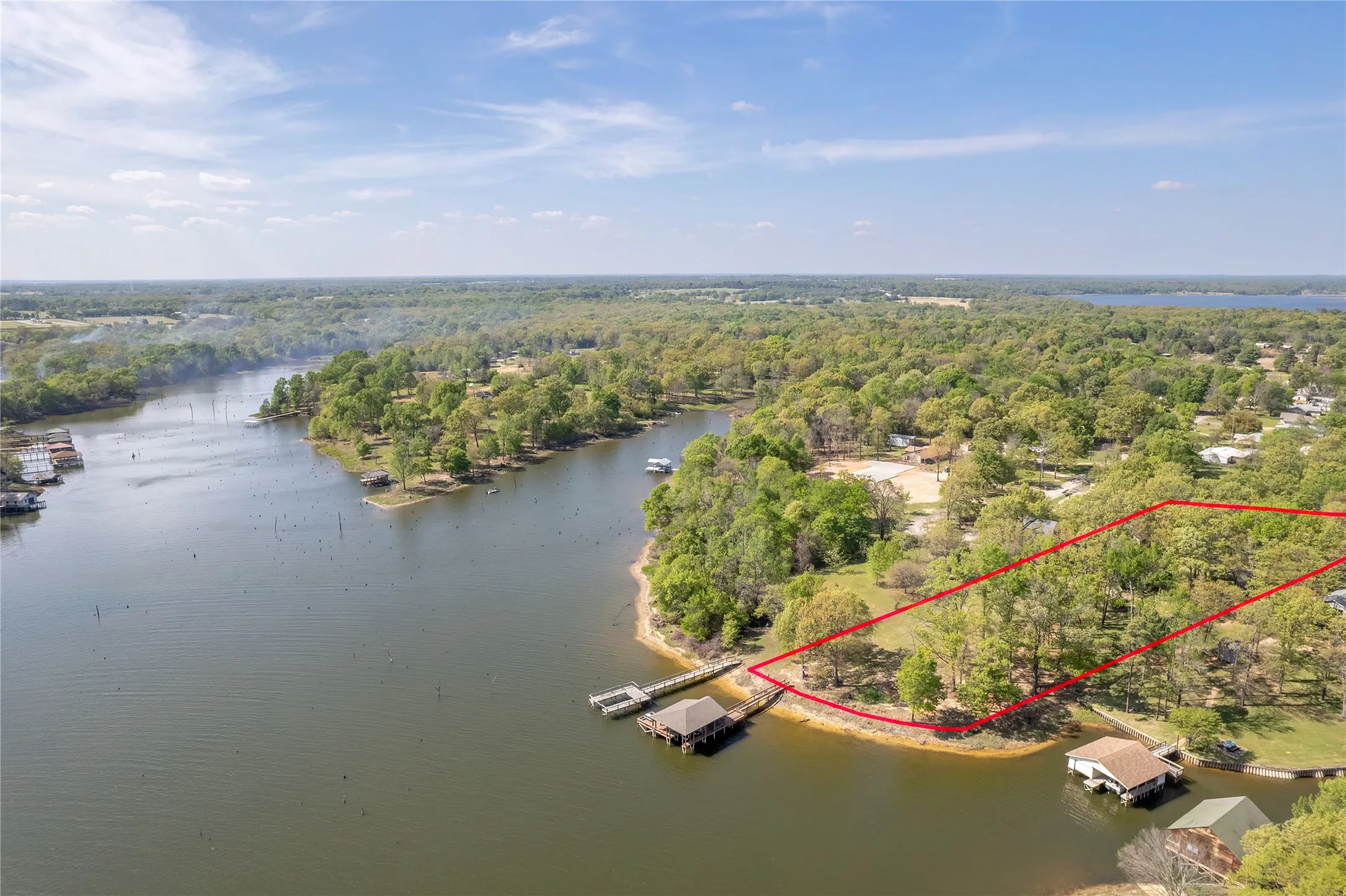 Aerial view of property and surrounding area with property boundaries highlighted and a nearby body of water