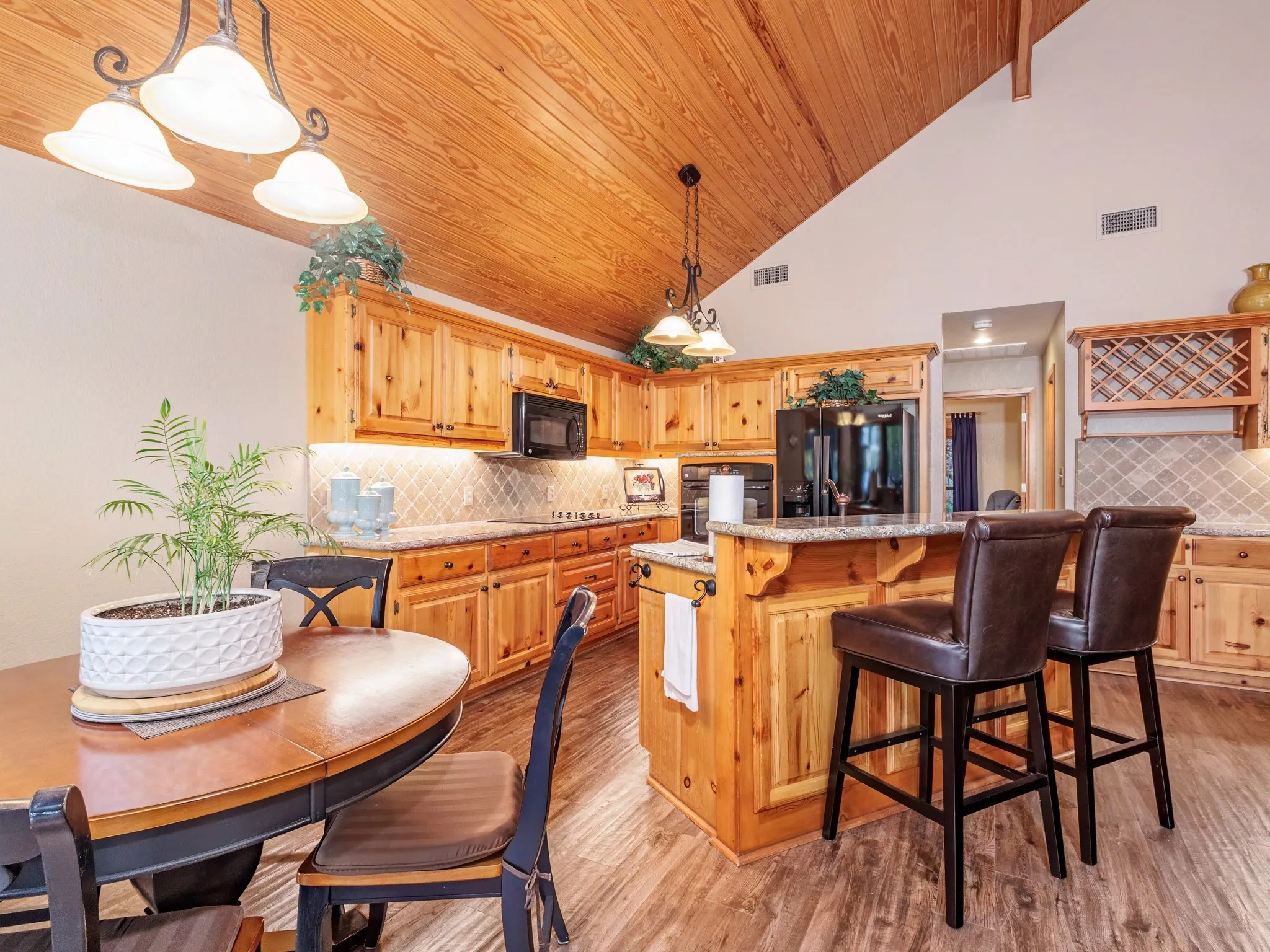 Kitchen featuring decorative backsplash, black appliances, a breakfast bar, a center island, and light wood finished floors