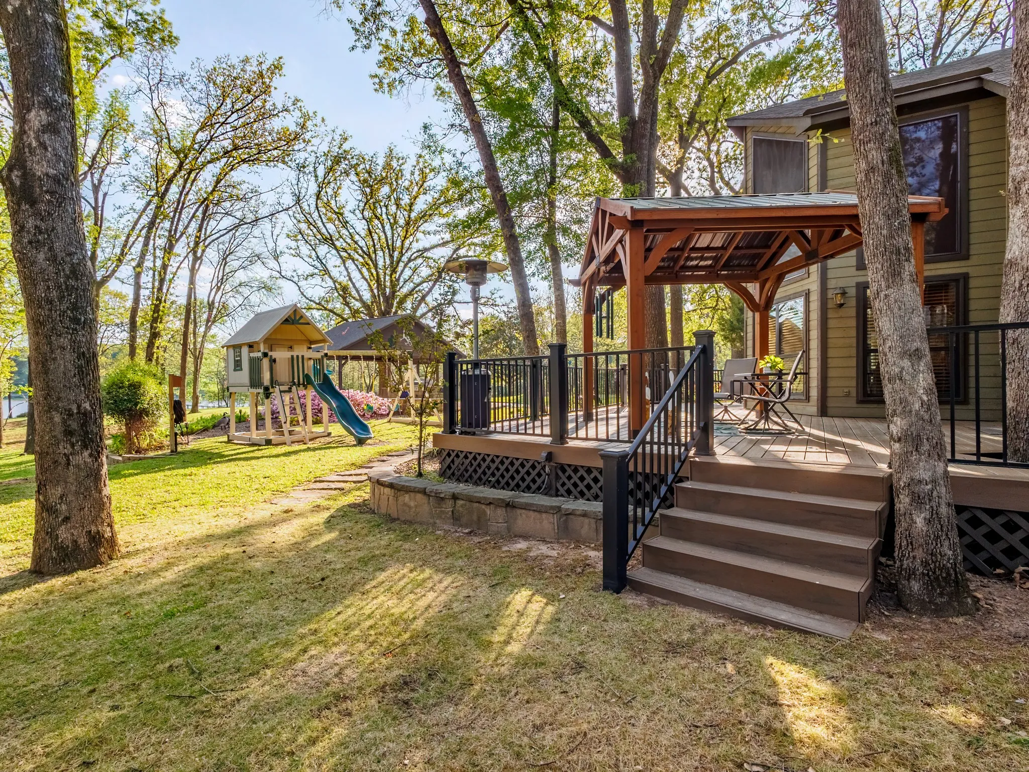View of green lawn with a gazebo, a wooden deck, and a playground