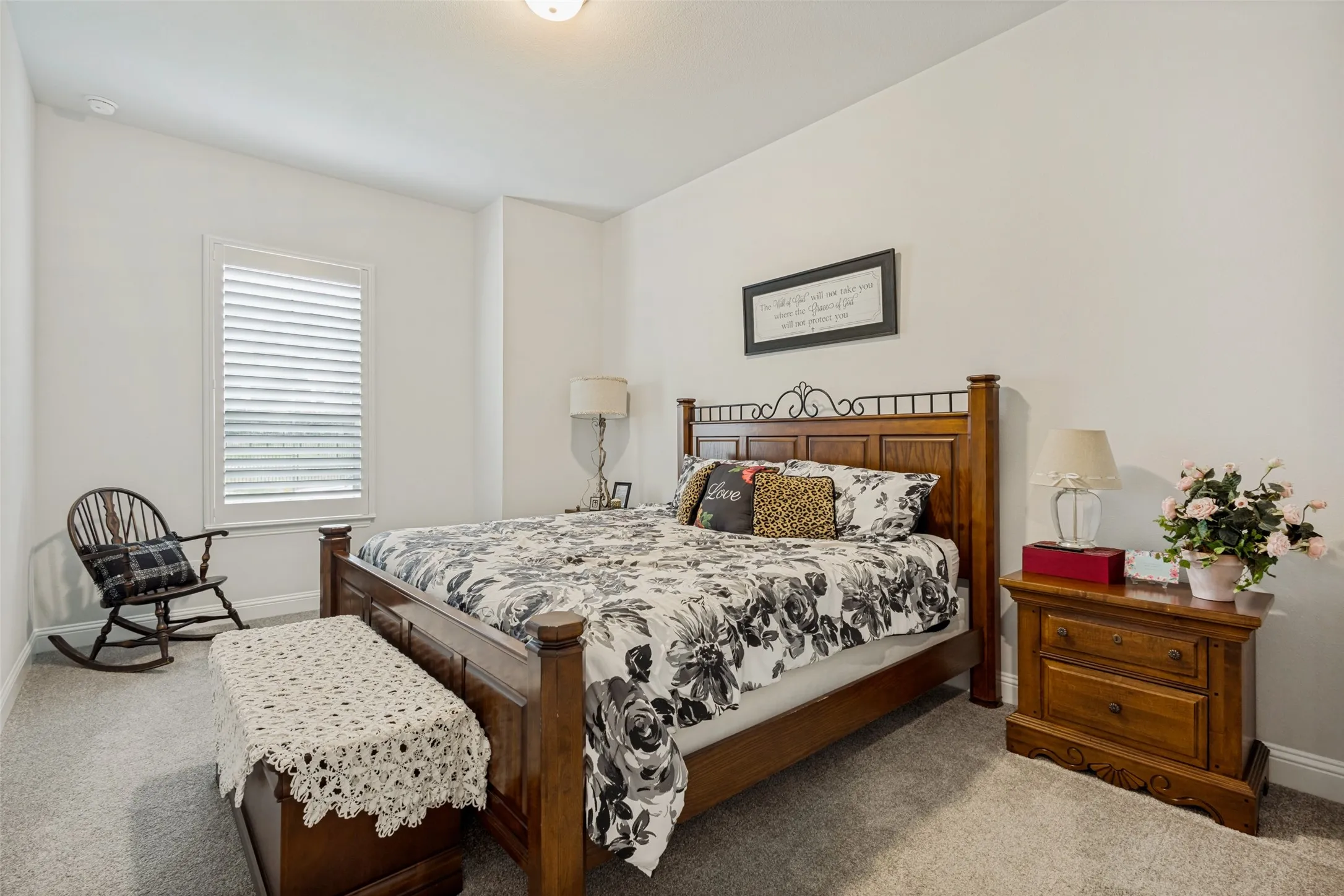 This room features light gray carpet flooring, a window with blinds, and white walls