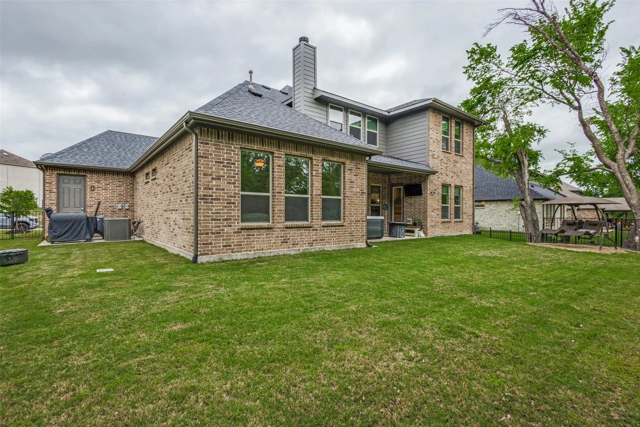 This property features a spacious backyard with a well-maintained lawn and mature trees