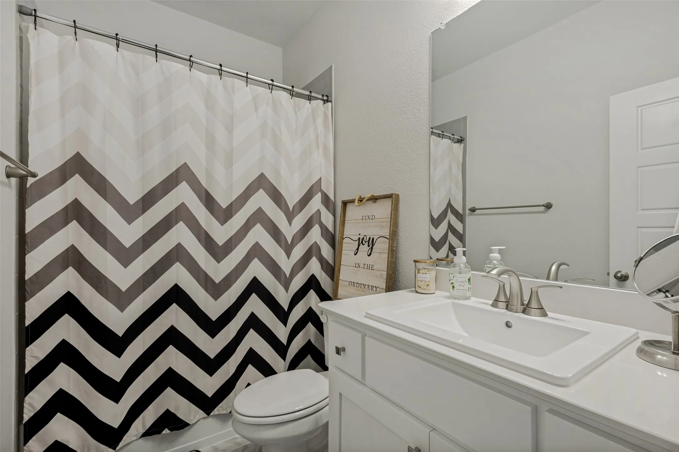 Bathroom with a white vanity featuring an integrated sink, a large wall-mounted mirror, and a toilet