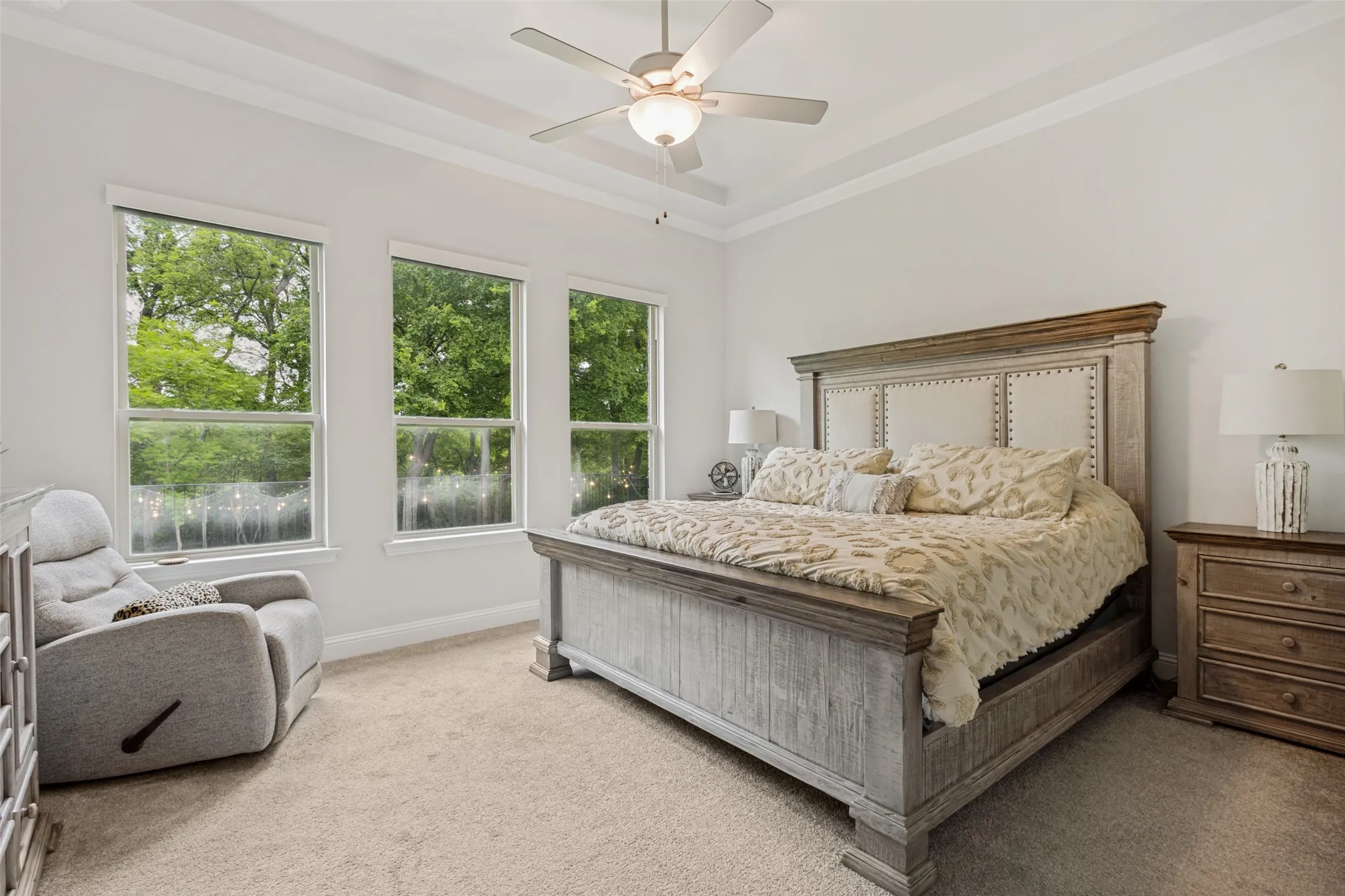 This room features three large windows providing abundant natural light, carpeted flooring, and a ceiling fan