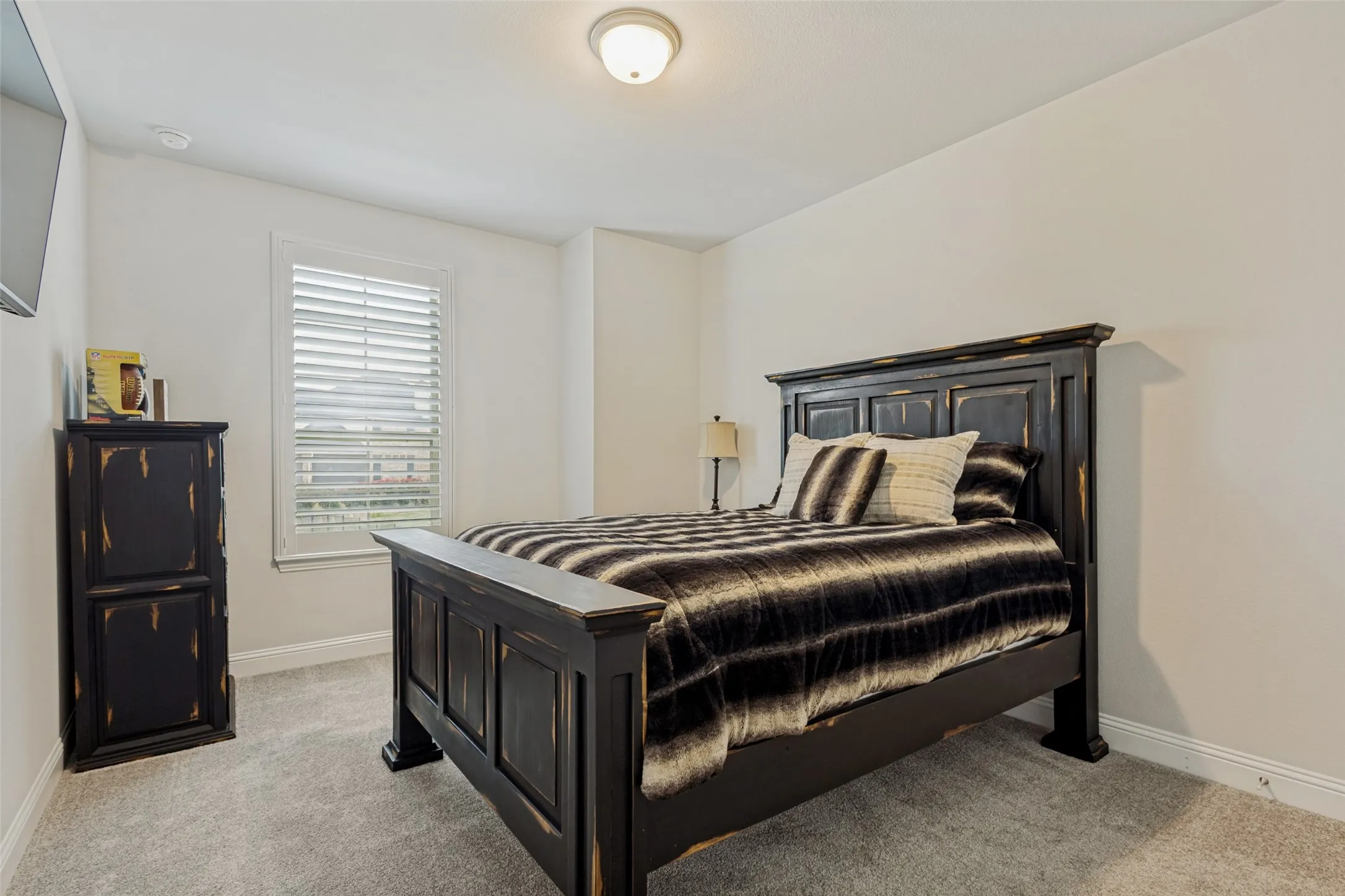 This bedroom features light-colored walls and carpet flooring, creating a bright and neutral space