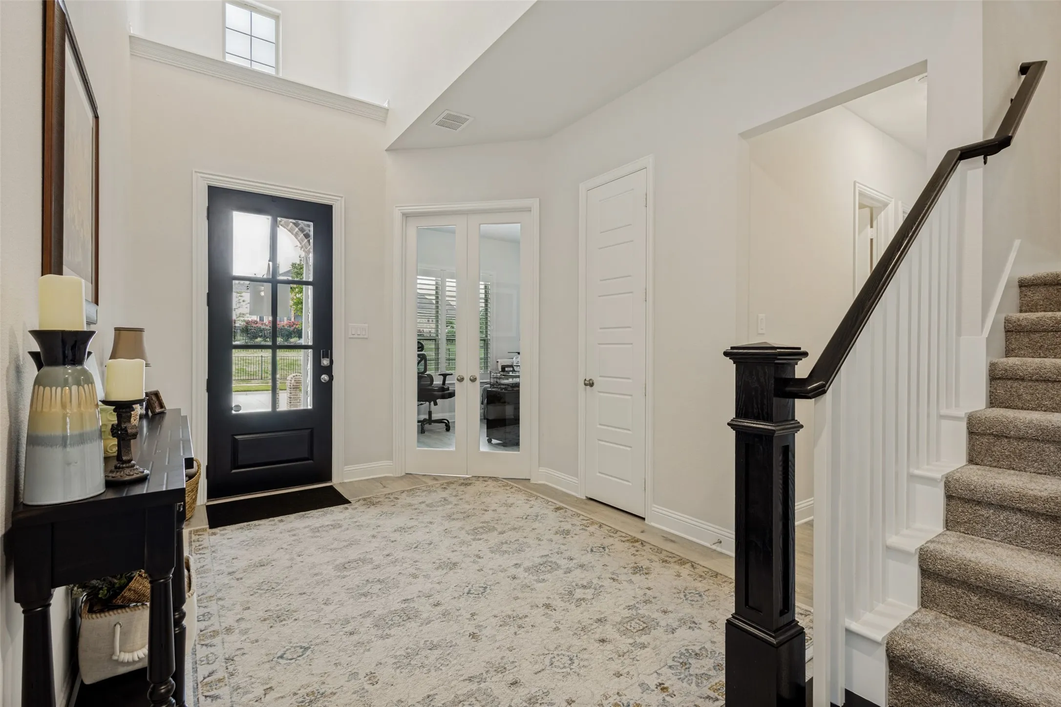 The property features a bright entryway with a dark front door, a staircase with a dark banister, and light-colored walls