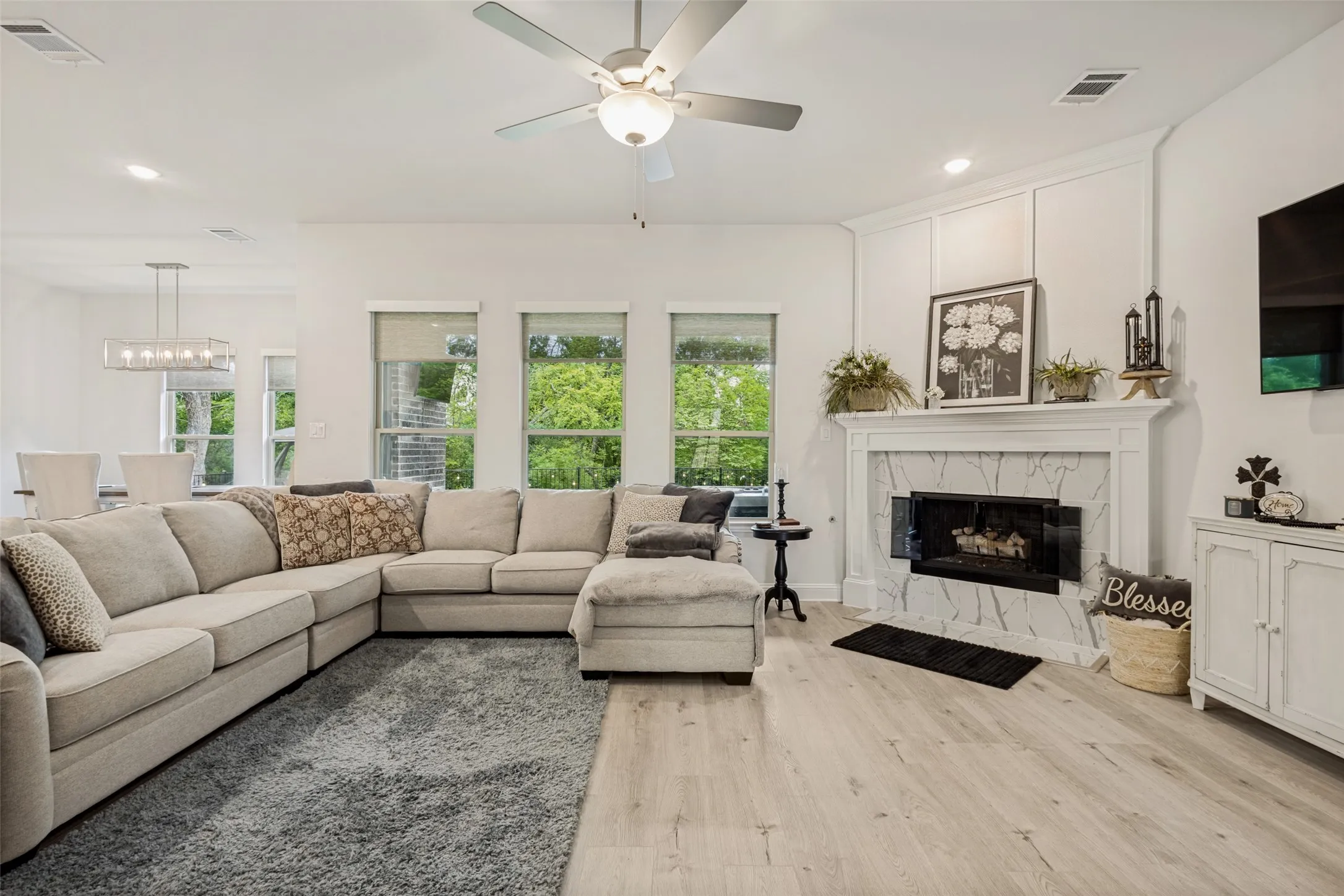 Living room featuring light-colored flooring, a ceiling fan, and a fireplace with a decorative mantel and marble-style surround