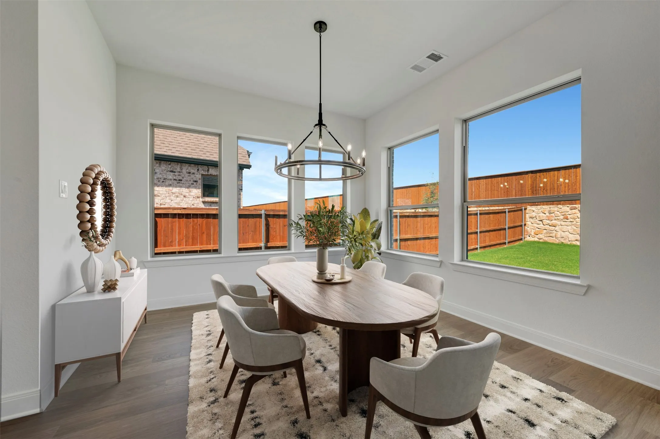 Spacious interior with wood-finish flooring, a contemporary chandelier, and large windows