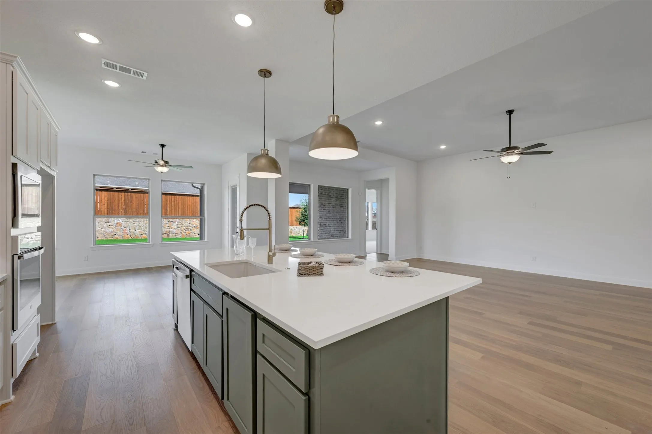 Kitchen island with an undermount sink, pendant lighting, and light-toned countertops