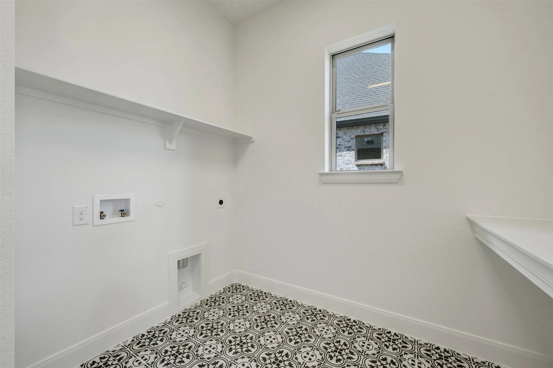 Built-in shelving, patterned floor tiles, dedicated laundry hookups, and a natural light window
