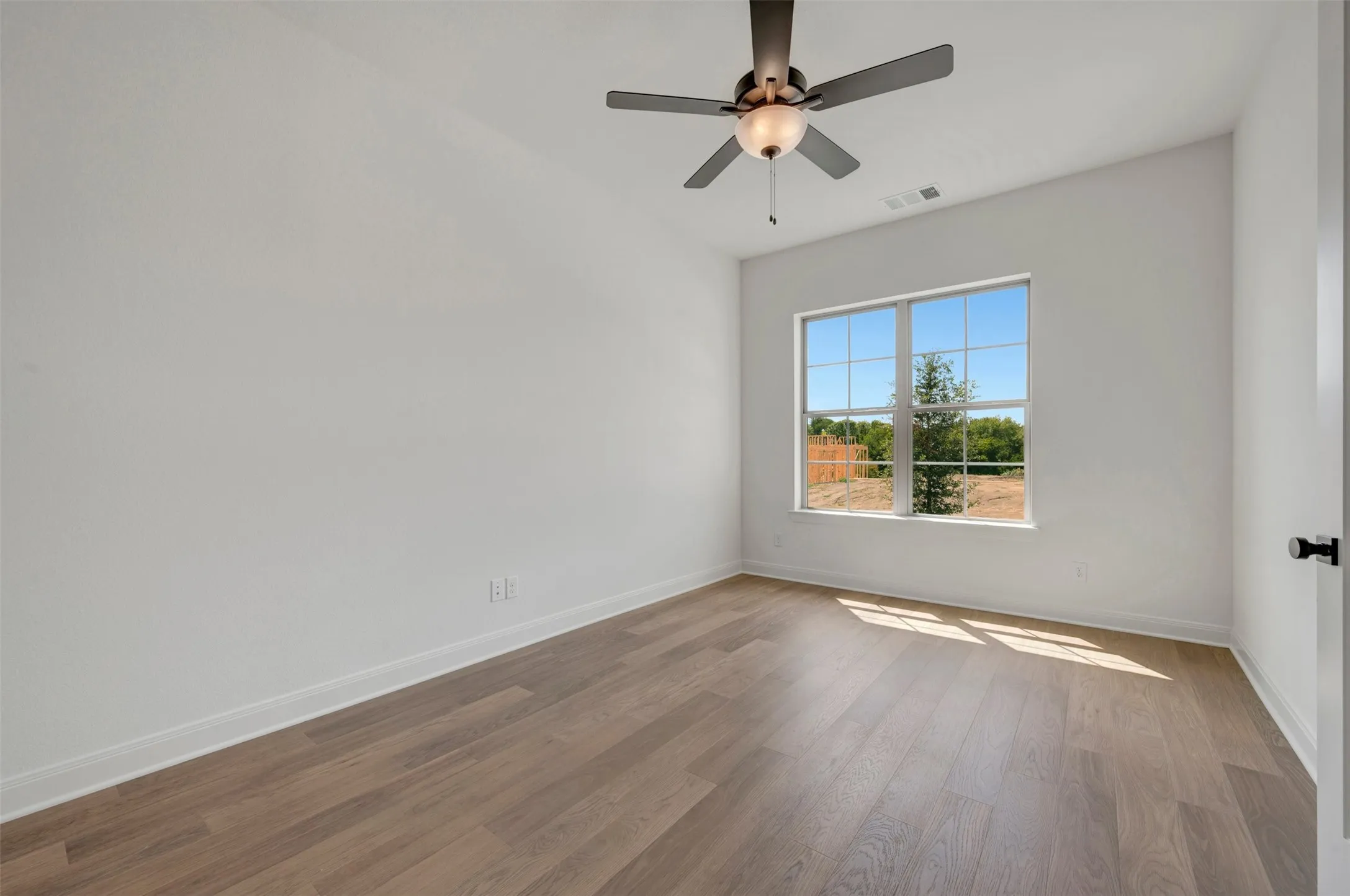 Wood-finish flooring, white walls, and a large window with multiple panes