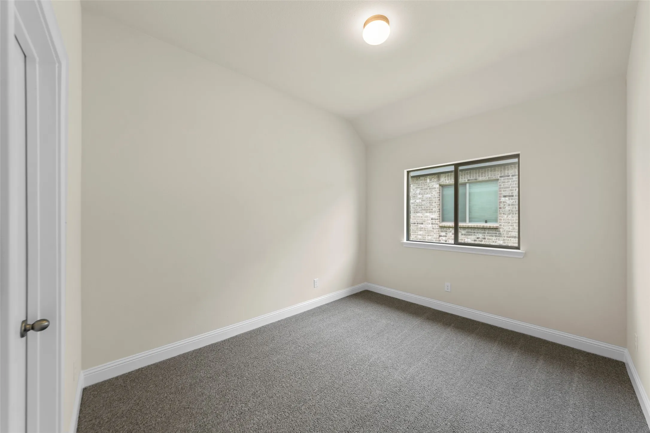 Bedroom featuring neutral wall color, gray carpeting, white baseboards, and a window with a view of exterior brickwork