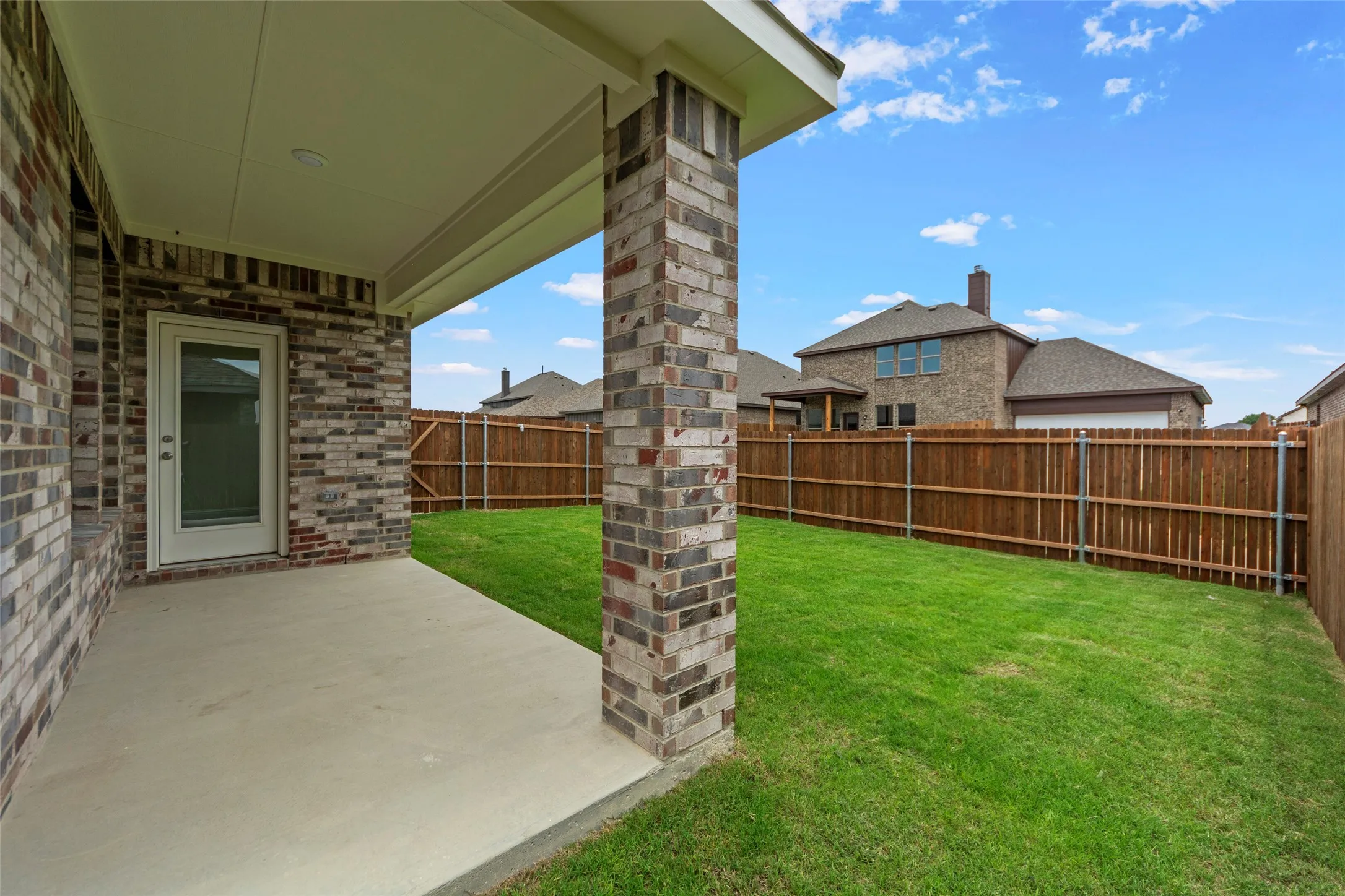 Covered patio with a concrete slab and brick columns