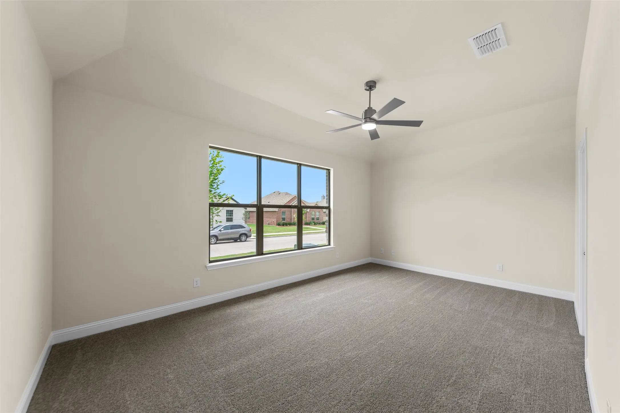 Spacious room featuring vaulted ceilings, neutral-toned walls, and plush carpeting