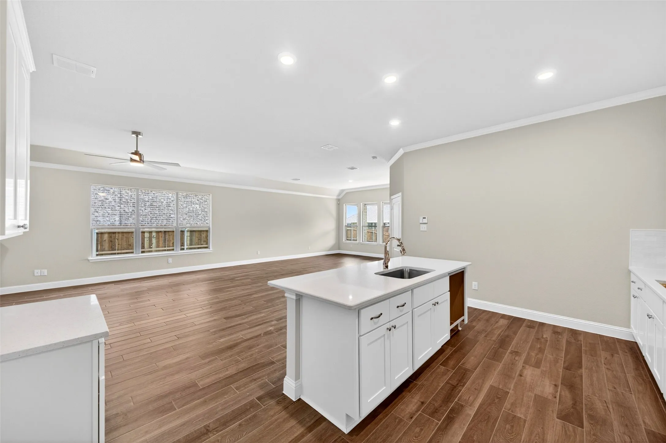 Open-concept living area with wood-finish flooring, recessed lighting, and crown molding