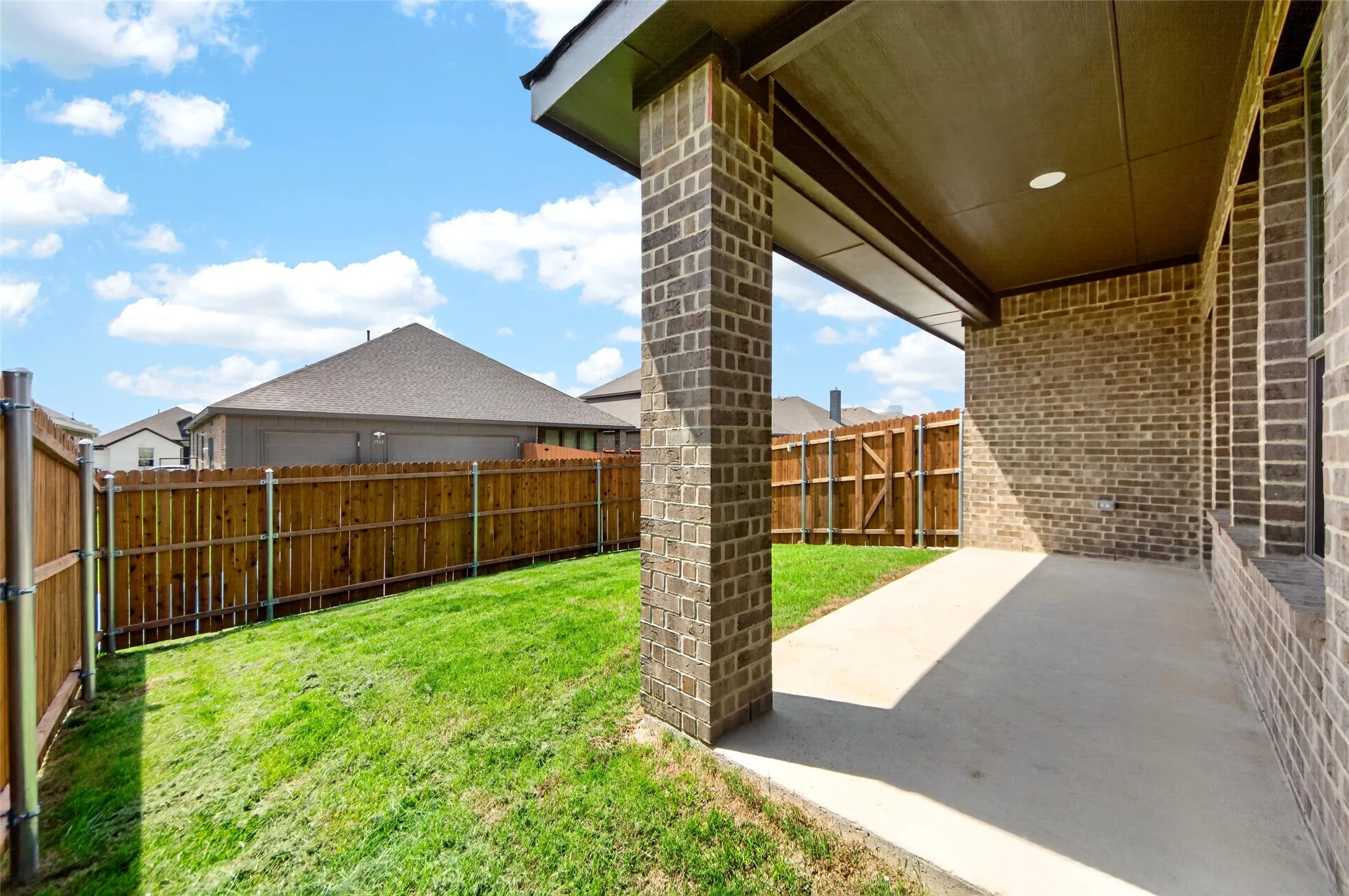Spacious covered patio featuring brick columns and exterior wall, recessed lighting, and a concrete surface