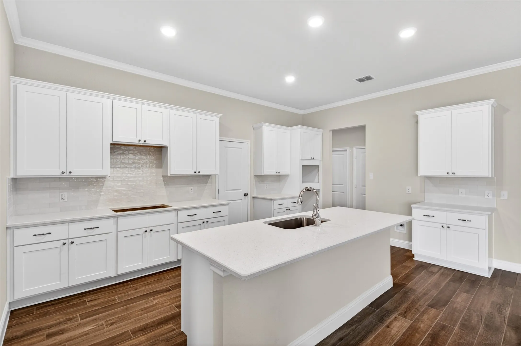 Contemporary kitchen featuring white shaker cabinetry, light-toned countertops, and wood-finish flooring