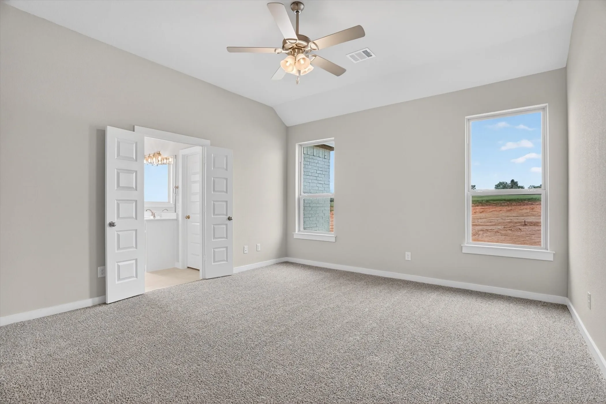 Spacious room featuring vaulted ceilings, light gray wall paint, and gray textured carpeting