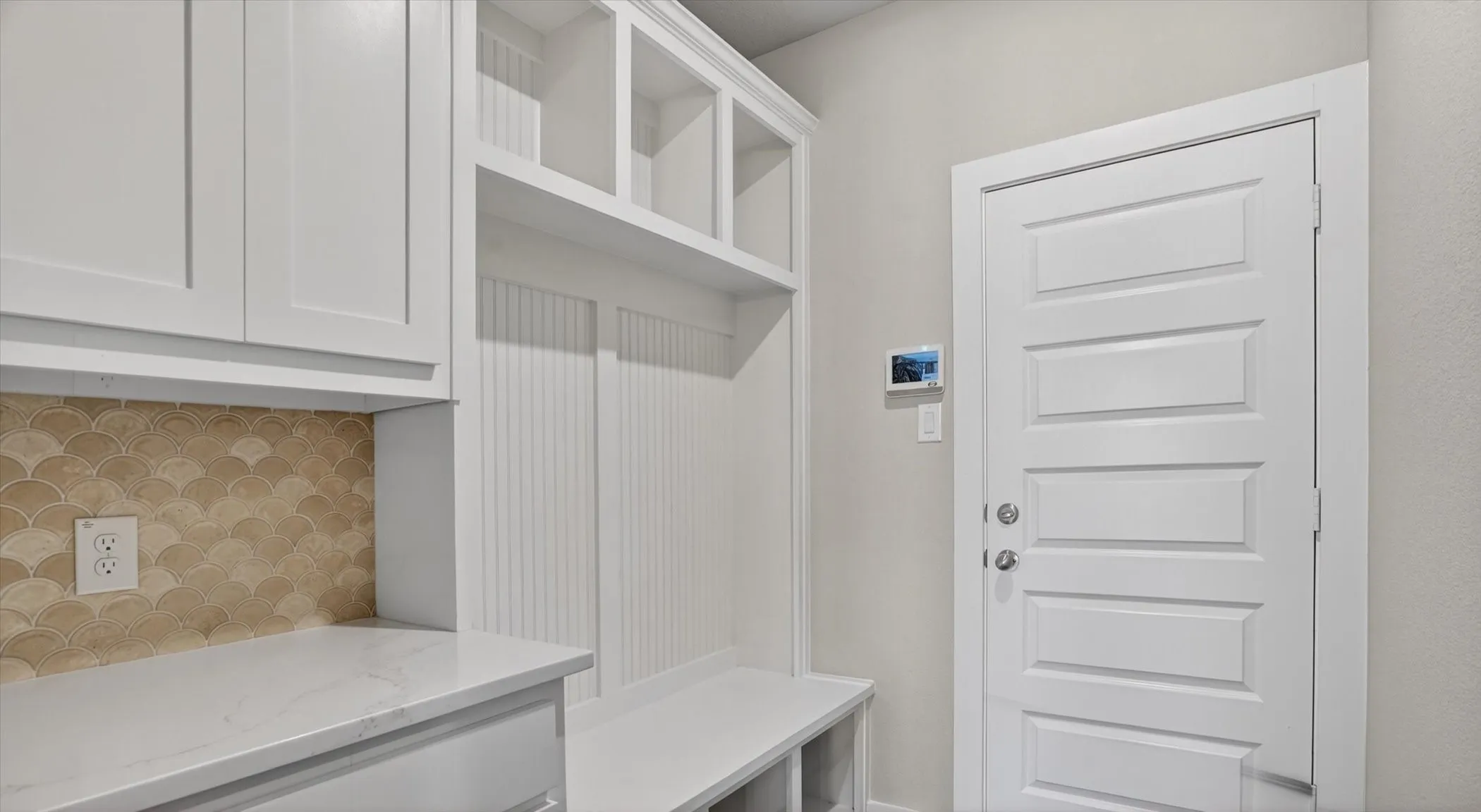 Built-in mudroom organization featuring upper cabinetry, open shelving, beadboard accents, and a bench with cubbies