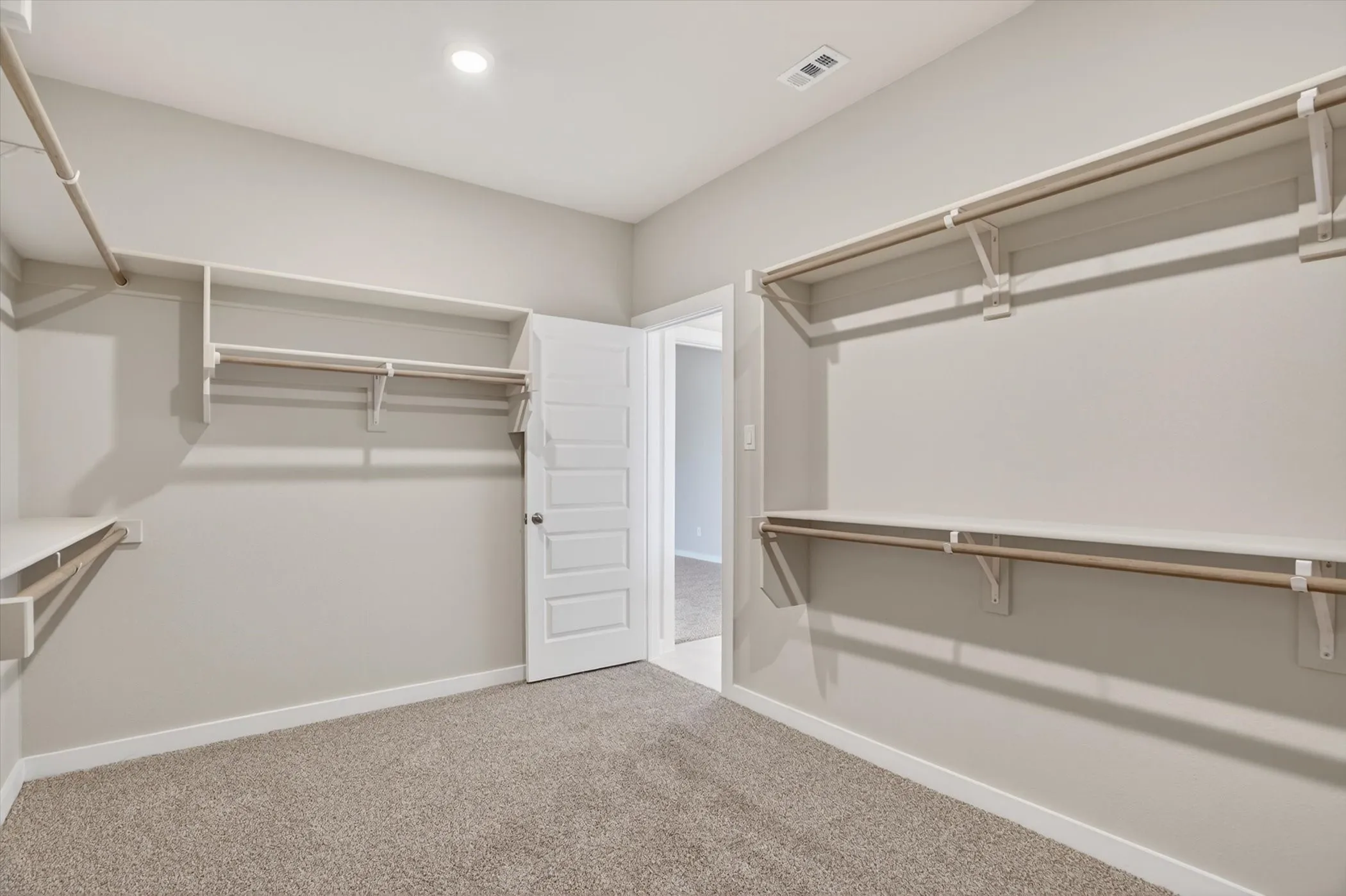 Walk-in closet featuring light gray walls, plush carpeting, and recessed lighting