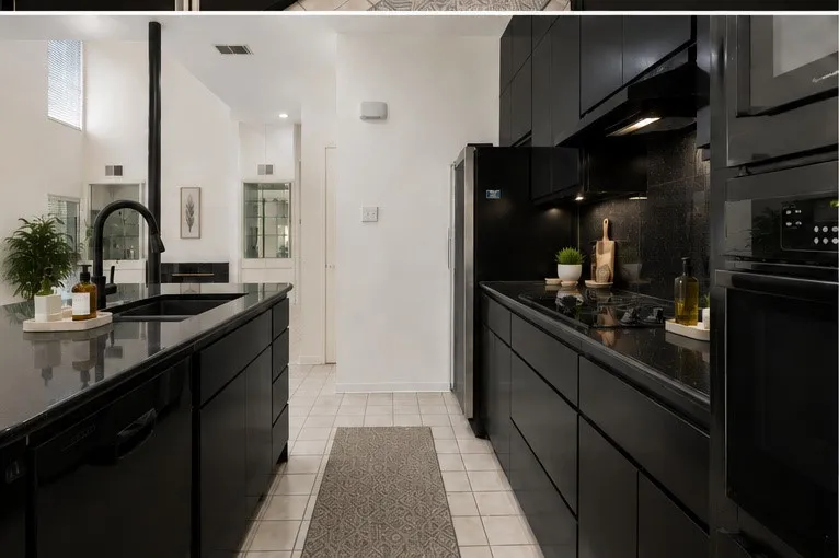 Kitchen featuring black cabinetry, black countertops, a black sink with a matte black faucet, and integrated black appliances