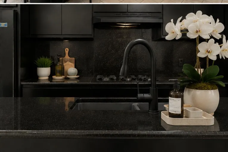 Black cabinetry with integrated hardware, dark speckled countertops, black undermount sink, and a matte black gooseneck faucet