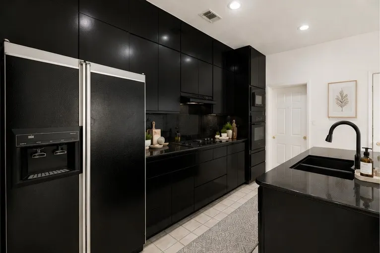 Sleek kitchen featuring black cabinetry, a built-in oven, microwave and induction stove top,black countertops, and a black sink with a matte black faucet