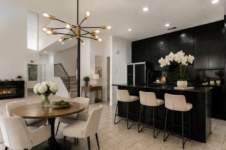 Virtually staged Dining area with actual chandelier, black shaker-style kitchen cabinetry, integrated black kitchen appliances, a kitchen island with seating
