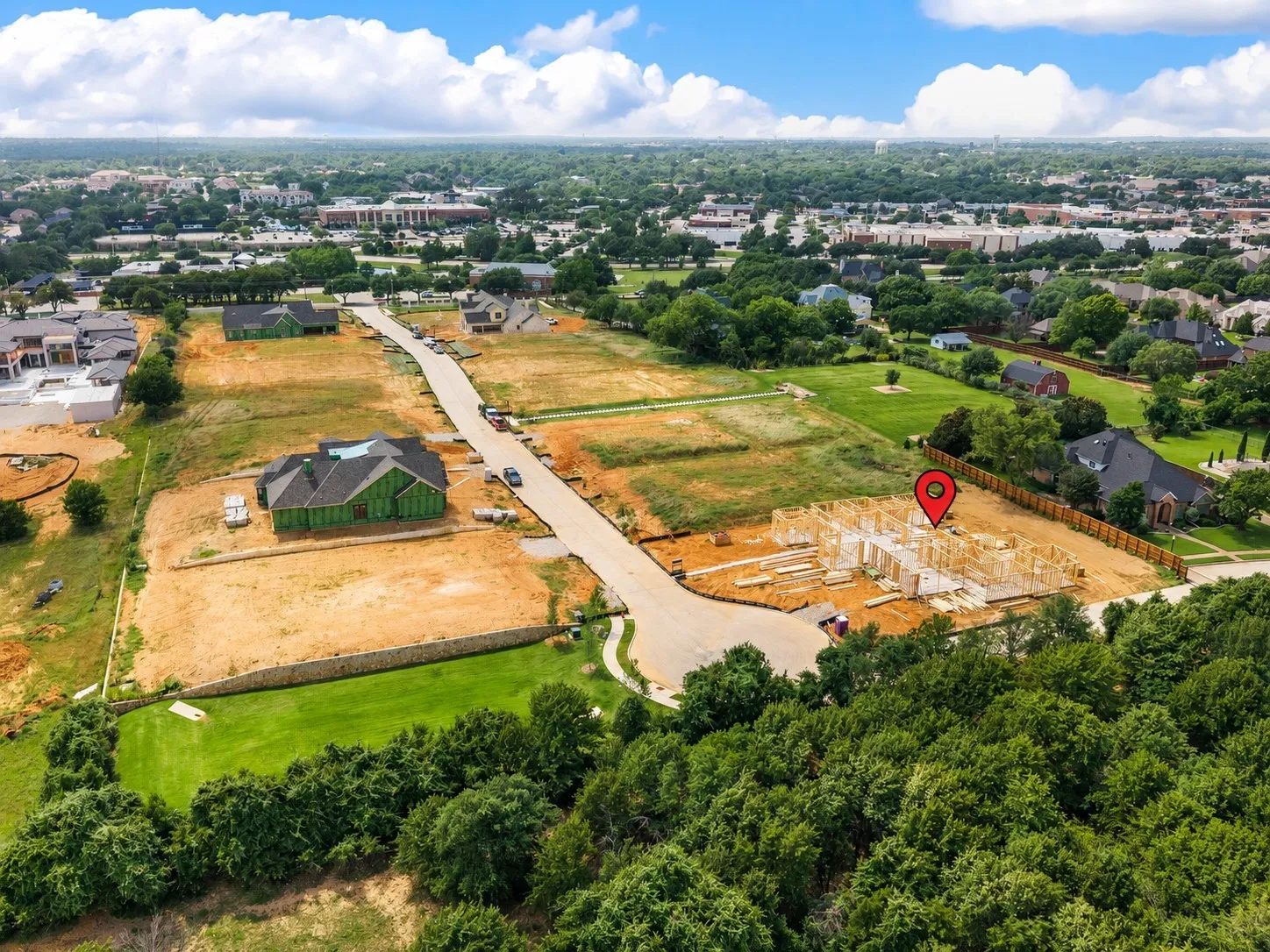 New construction opportunity featuring a framed structure, surrounding undeveloped land, a paved street, and established perimeter trees