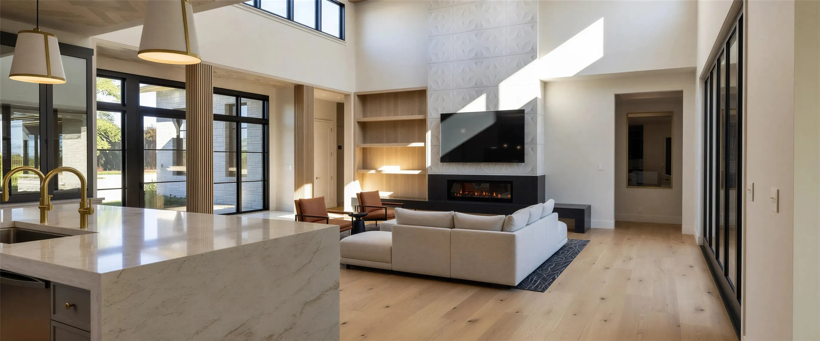 Living area with a high ceiling, light wood-style flooring, a glass covered fireplace, and built in features