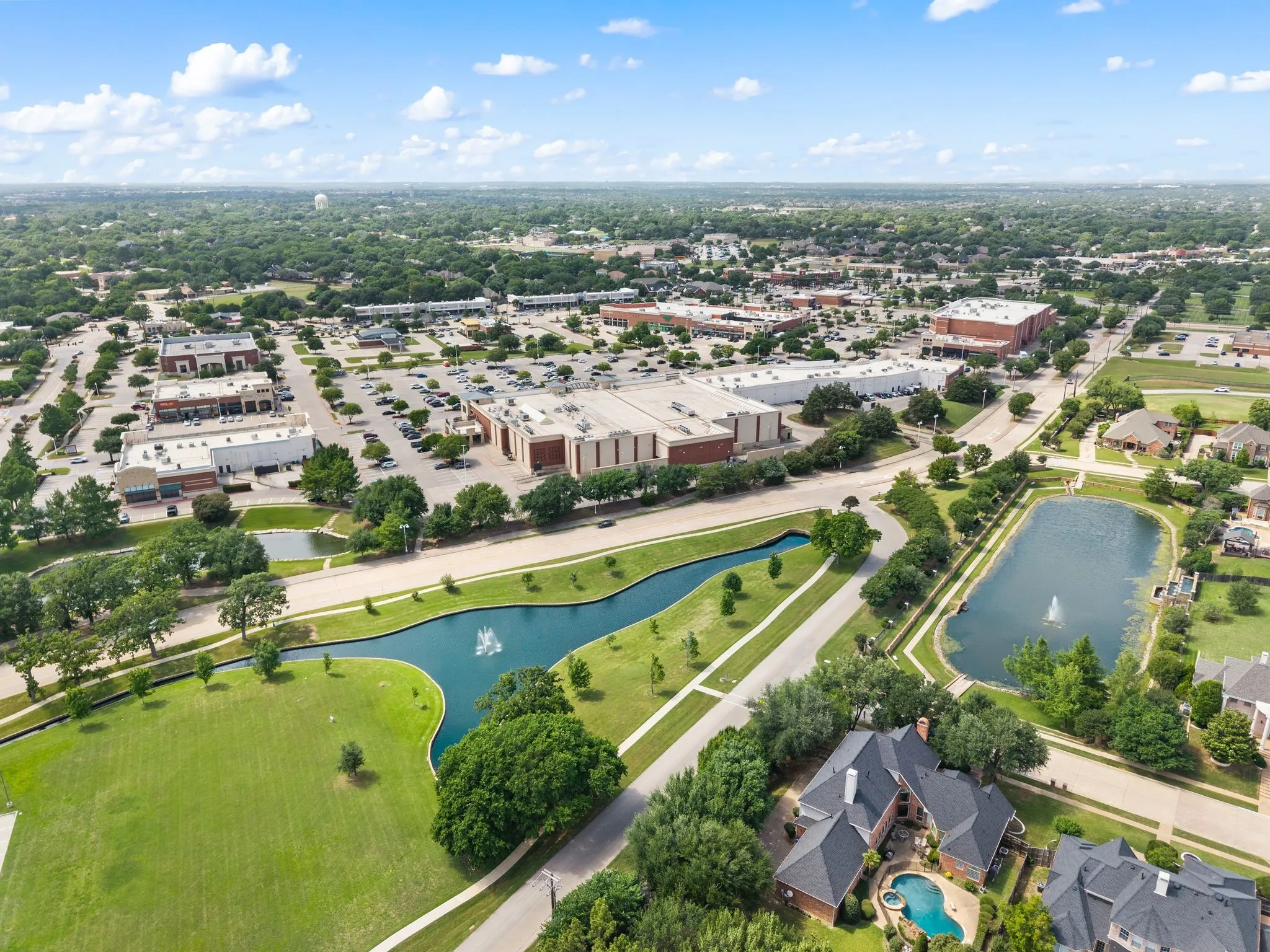 Aerial perspective showcasing a residential area with a prominent, winding waterway featuring fountains