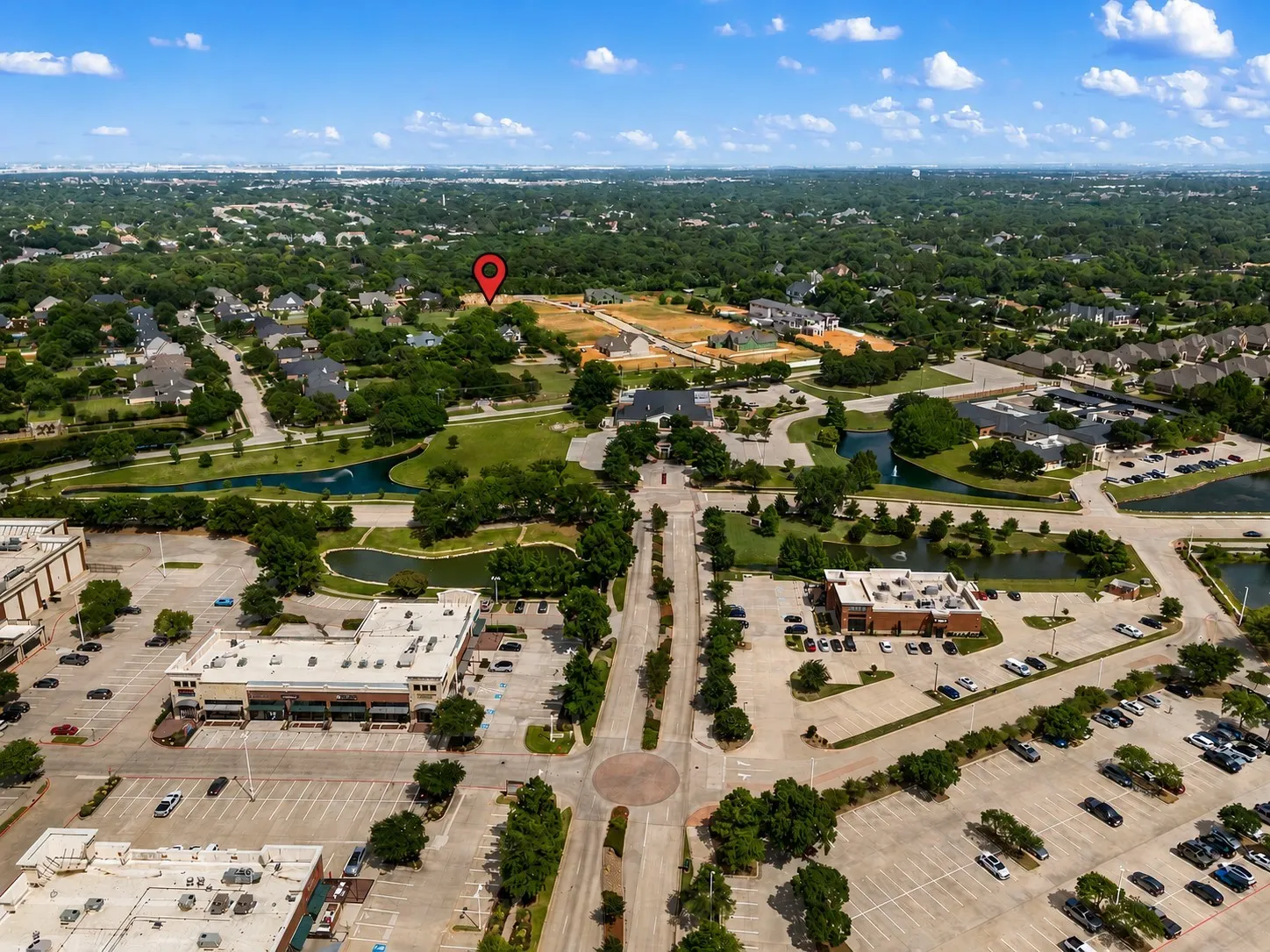 Aerial perspective showcasing a developed suburban landscape featuring residential areas, commercial buildings, and extensive green spaces with water features