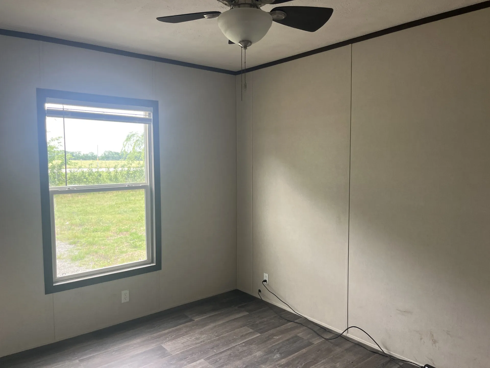 Interior room featuring a single window, a ceiling fan with light, and wood-finish flooring