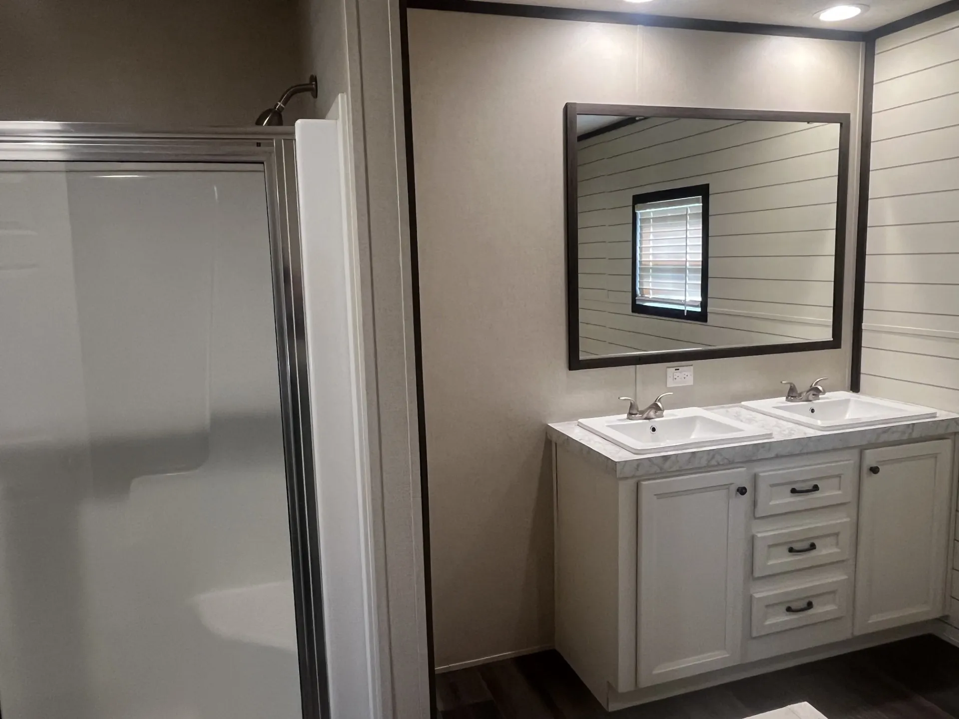 Double vanity with white cabinetry, dual undermount sinks, and a framed mirror
