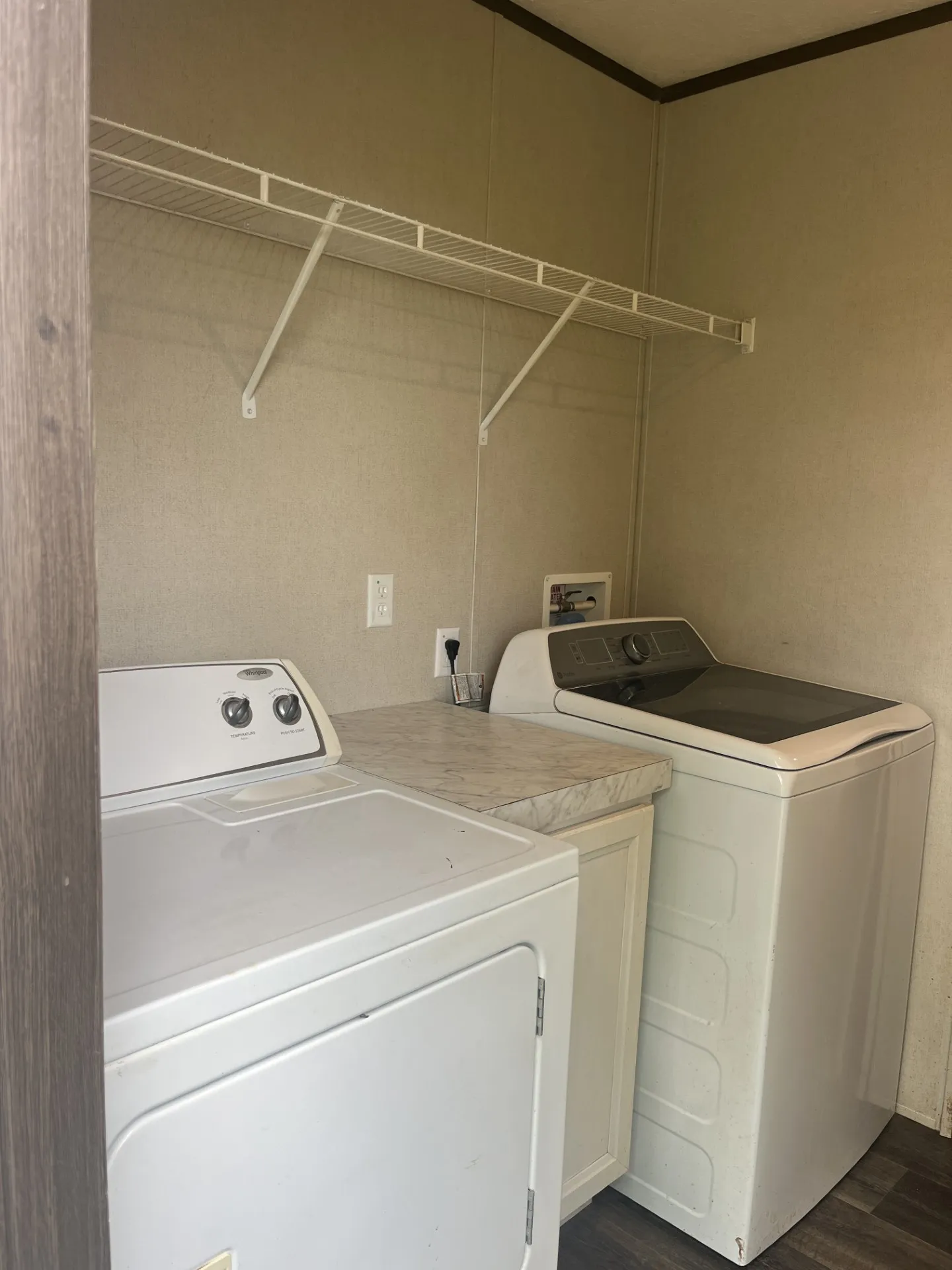 Dedicated laundry area featuring a white wire shelving unit, wood-finish flooring, and a base cabinet with a countertop
