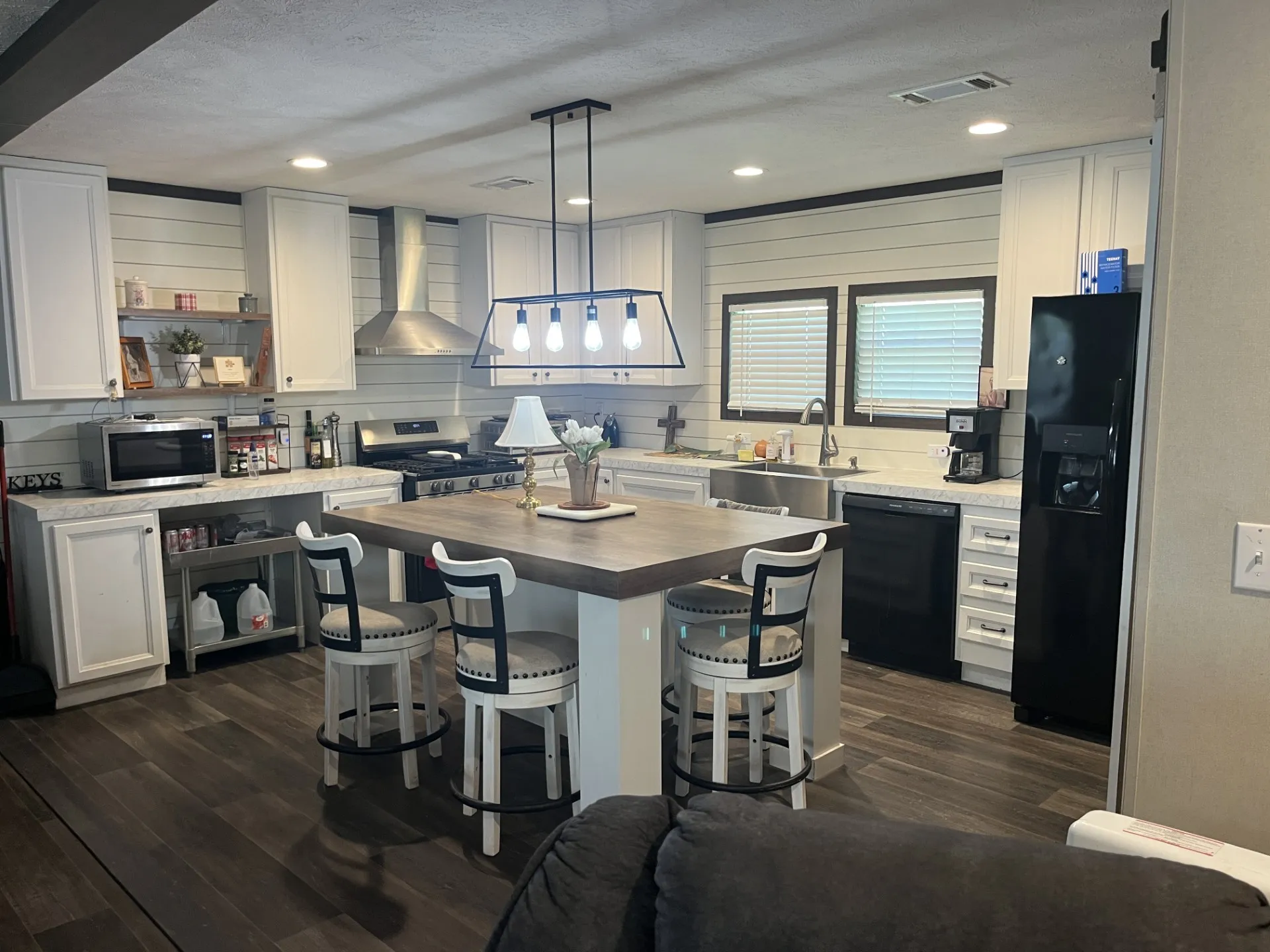 Kitchen featuring butcher block countertops, dark wood-type flooring, a breakfast bar area, and black appliances