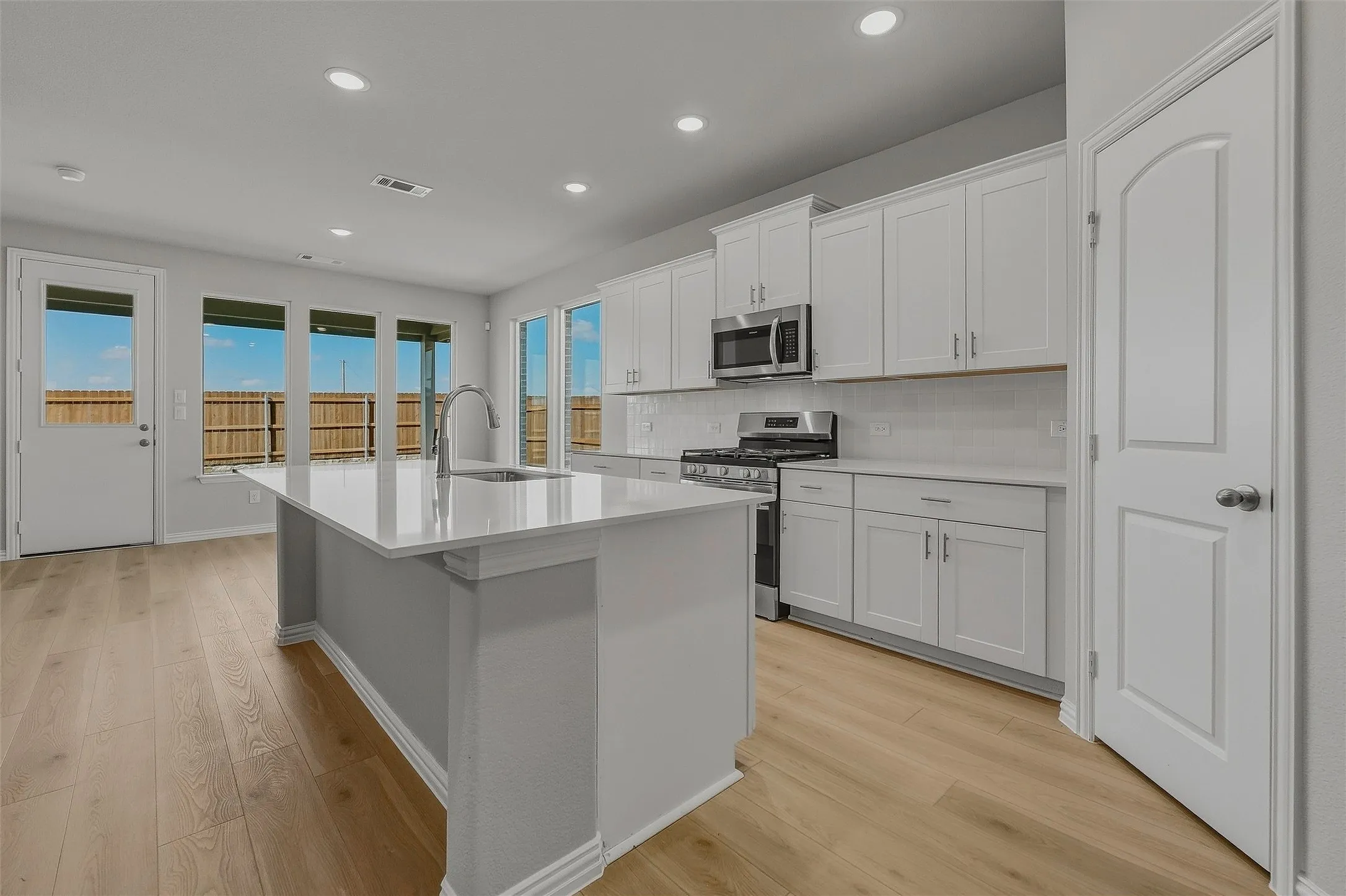 Kitchen featuring a center island, white cabinetry, stainless steel appliances, wood-finish flooring, and recessed lighting