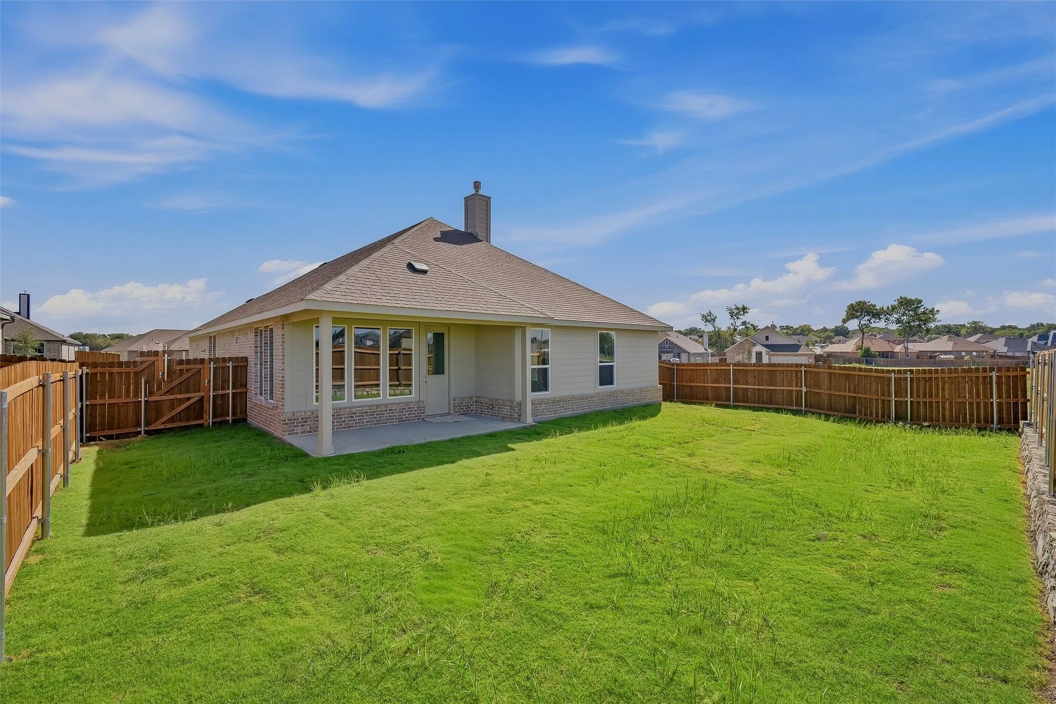 Expansive backyard featuring a manicured lawn, full perimeter fencing, and a concrete patio