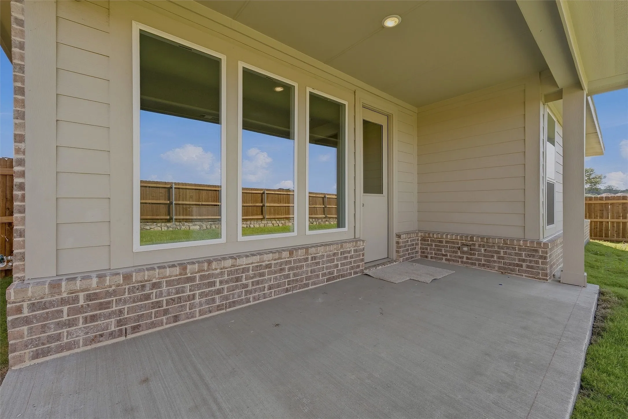 Covered concrete patio with recessed lighting, brick detailing, and horizontal siding