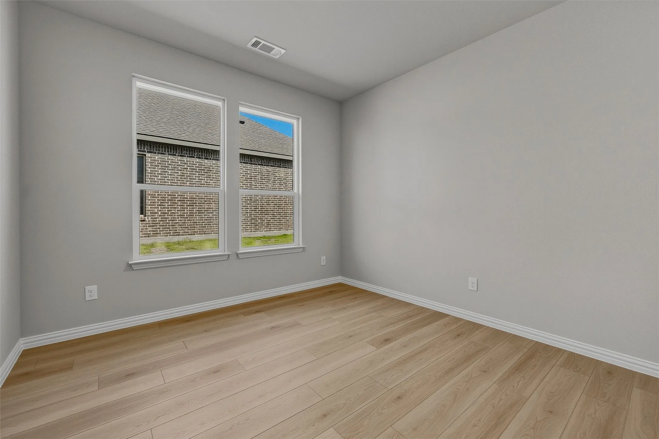 Neutral wall tones, wood-finish flooring, two large windows, white trim