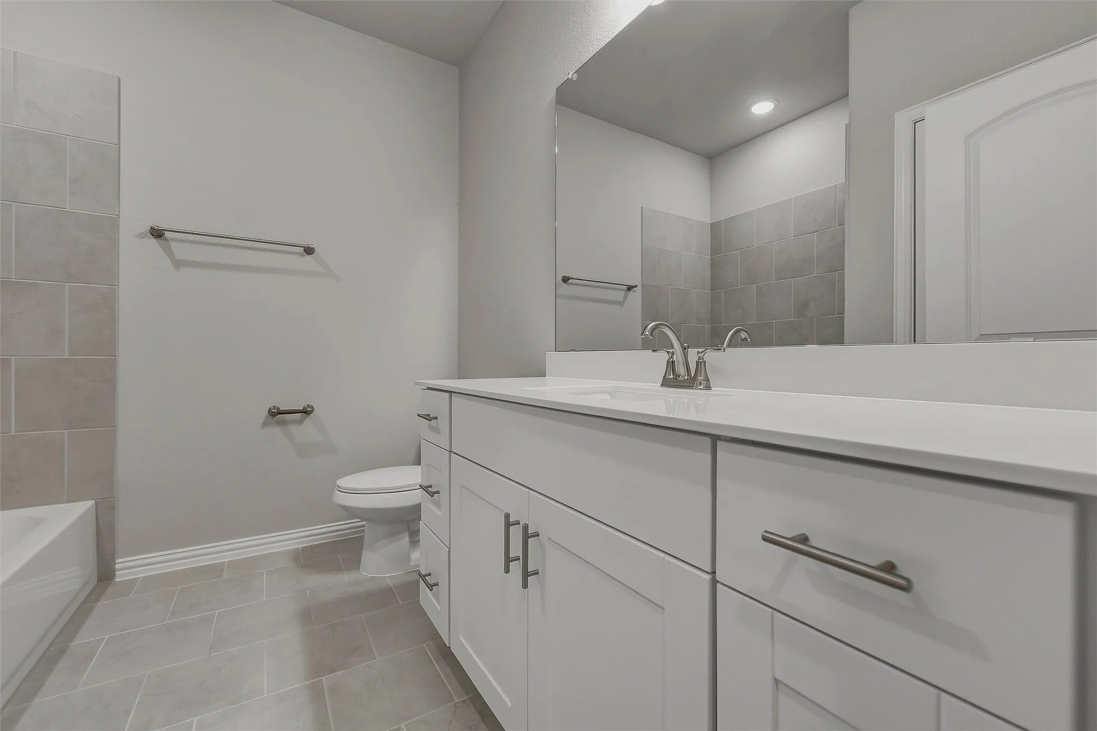 White vanity with brushed nickel hardware, white countertop, undermount sink, and wall-mounted mirror