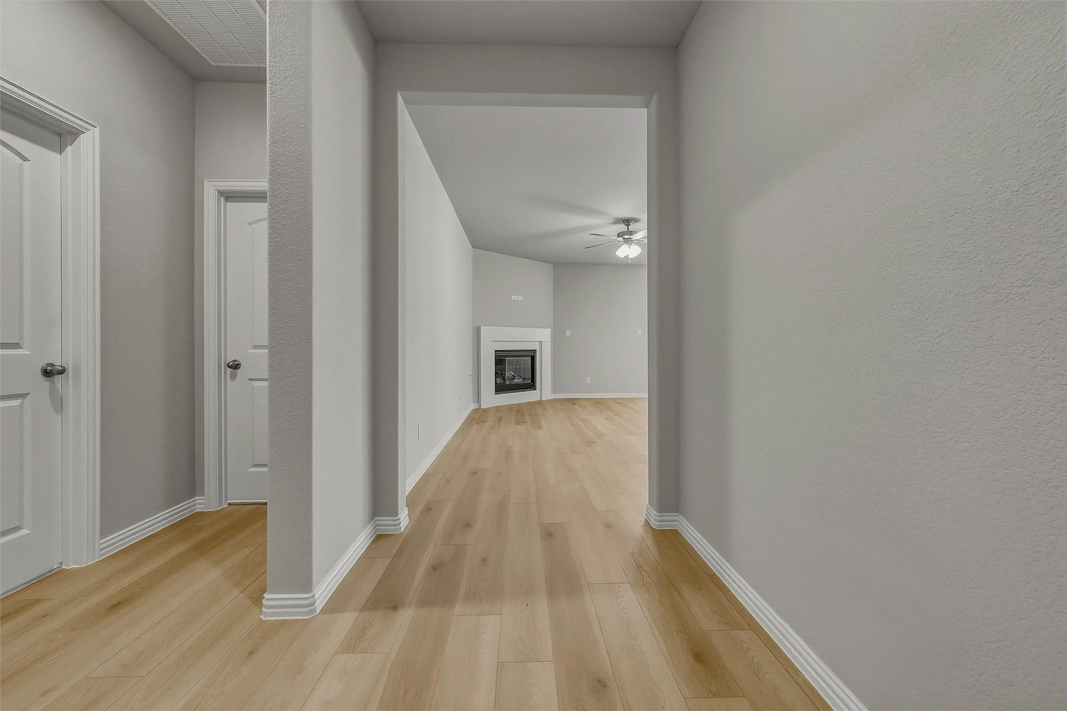 Wood-finish flooring throughout, light gray wall paint, white trim, and white interior doors